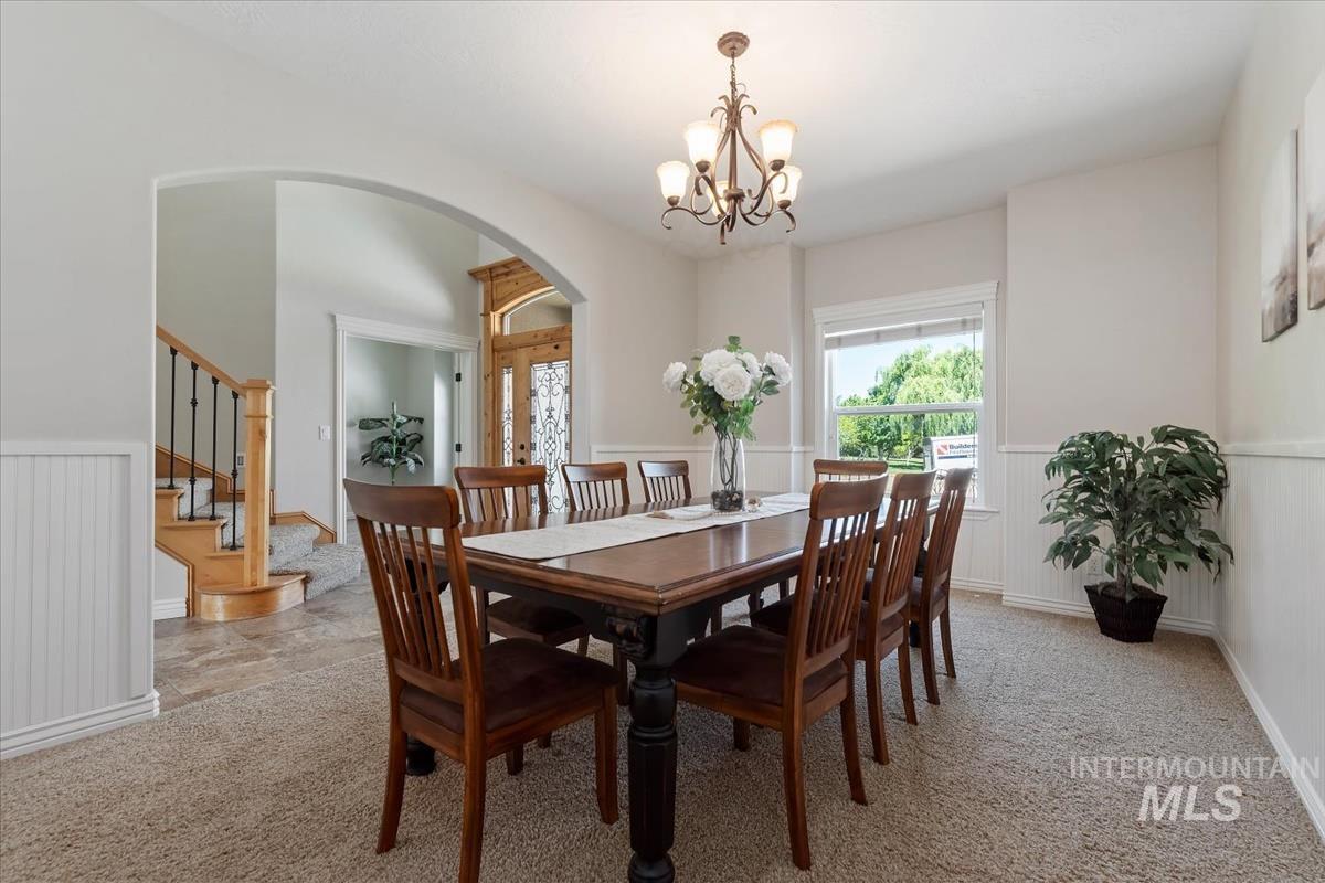 Dining area featuring wainscoting, a bay window, and a chandelier