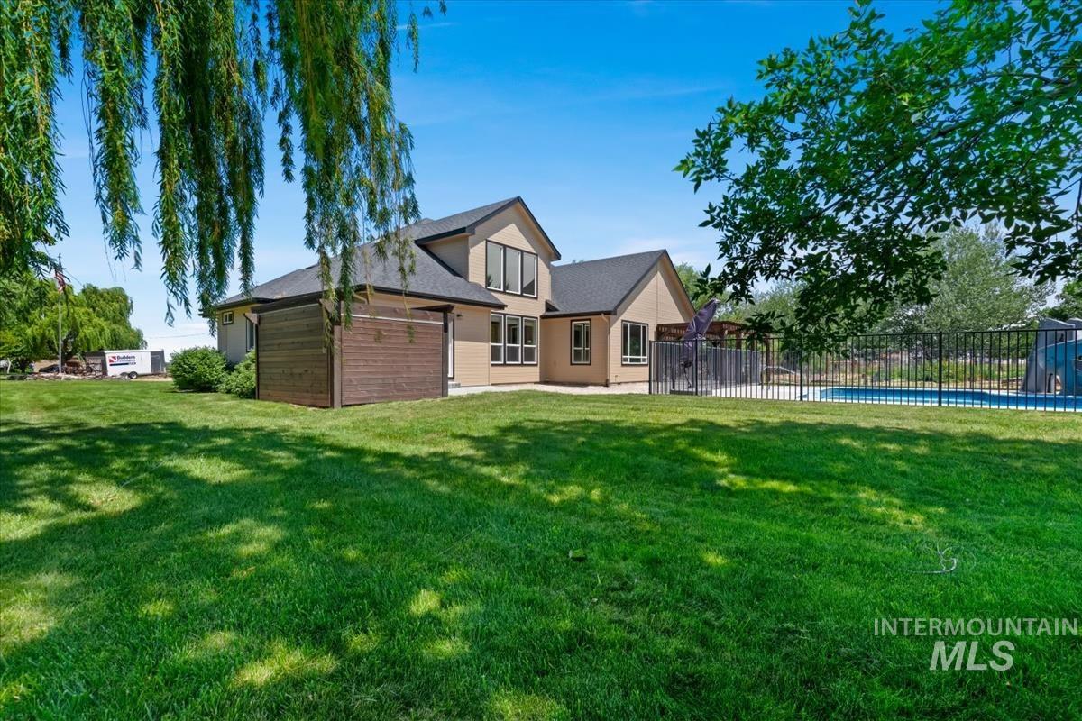 Expansive lawn with mature trees and a fenced pool area