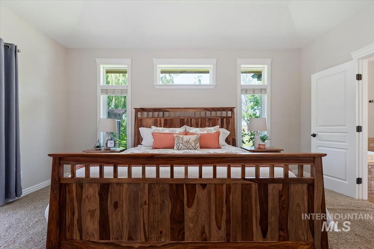 Spacious room featuring vaulted ceilings, light neutral wall paint, three windows with white trim, and light beige carpet