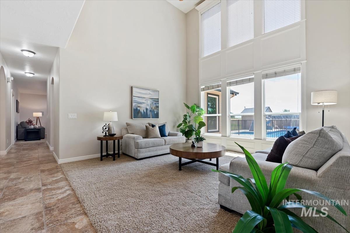 Living area featuring a high vaulted ceiling and expansive window wall with blinds