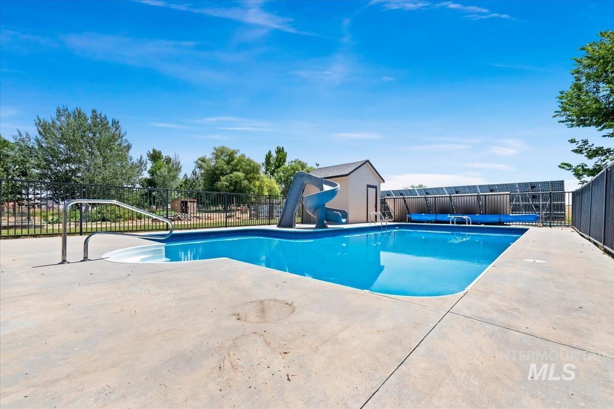 In-ground swimming pool with a concrete surround, featuring a built-in slide and entry steps