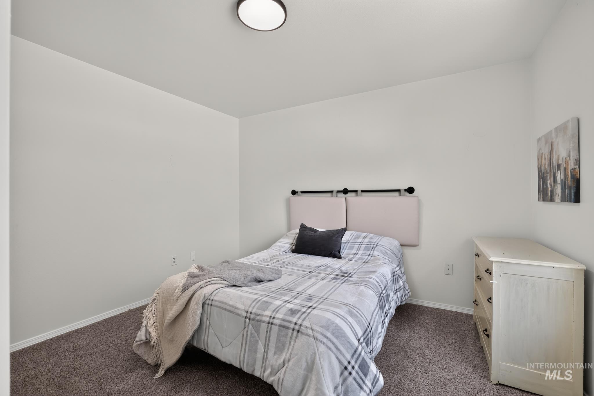 Neutral wall paint with dark carpet flooring, featuring a built-in wall sconce