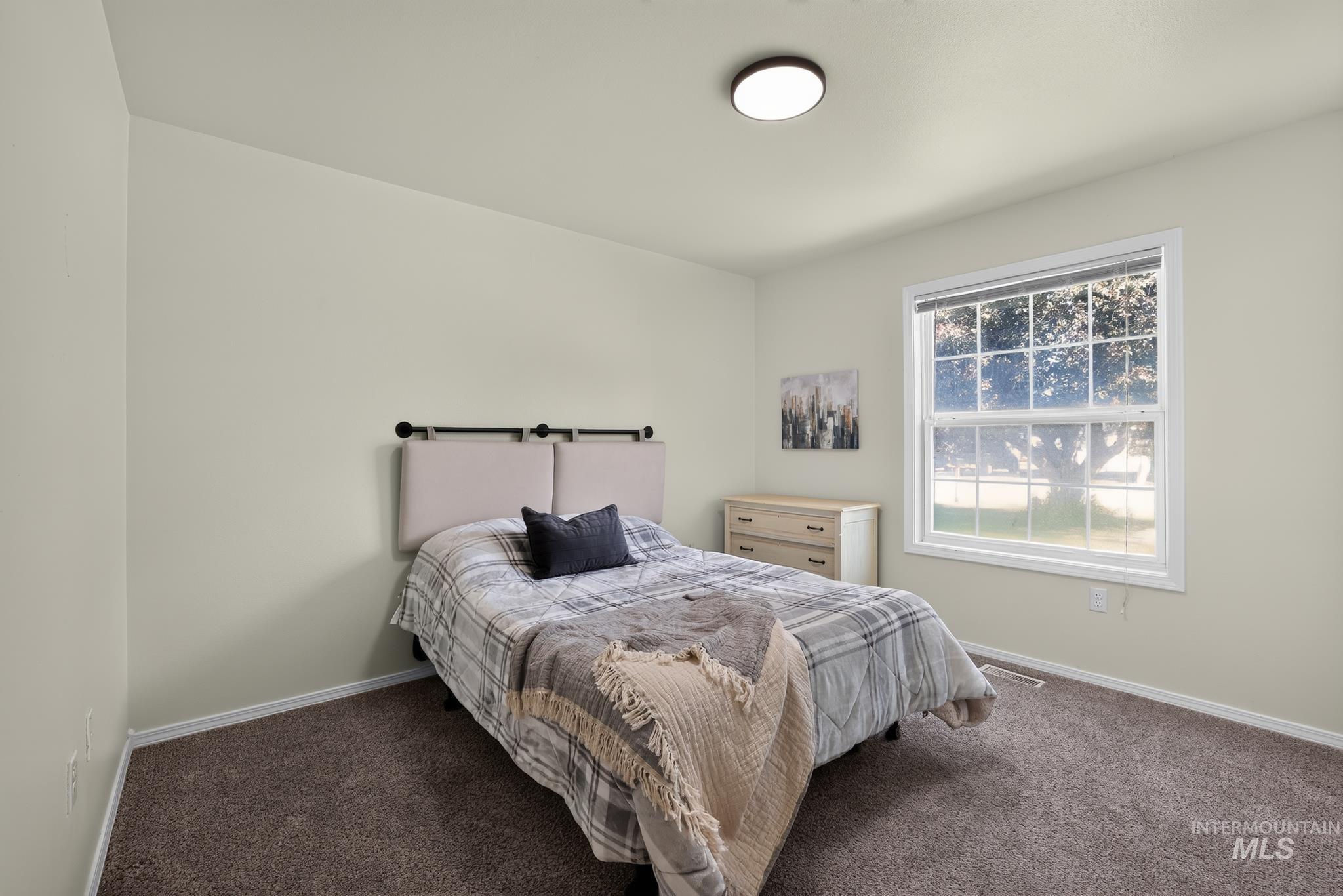Carpeted bedroom with a single window featuring white trim