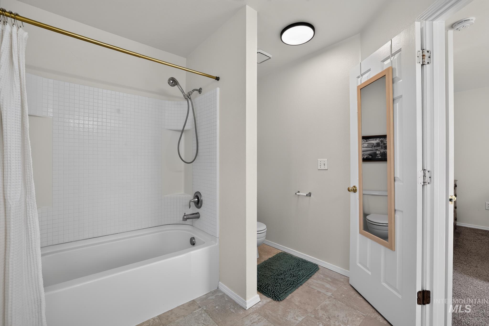 Full-size bathtub with a built-in shower featuring white square tile-patterned surround