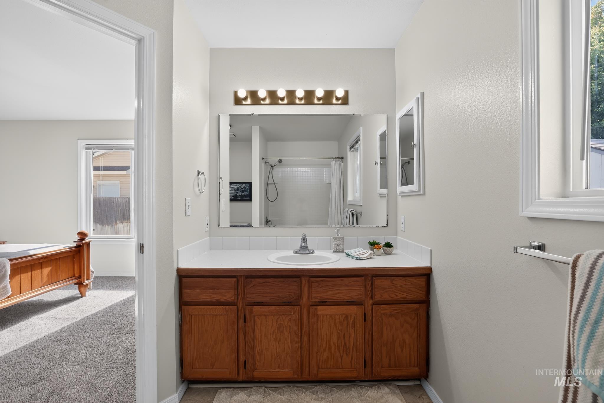 Bathroom vanity featuring a single basin sink, laminate countertop, and wood-finish cabinetry