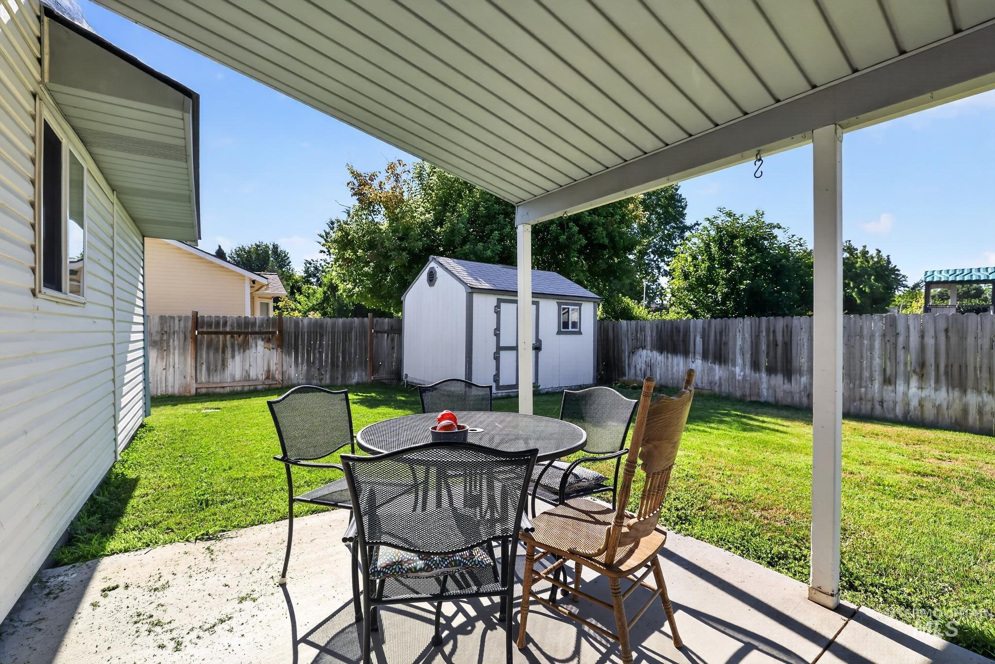 Covered patio with concrete flooring, offering direct access to a fenced backyard
