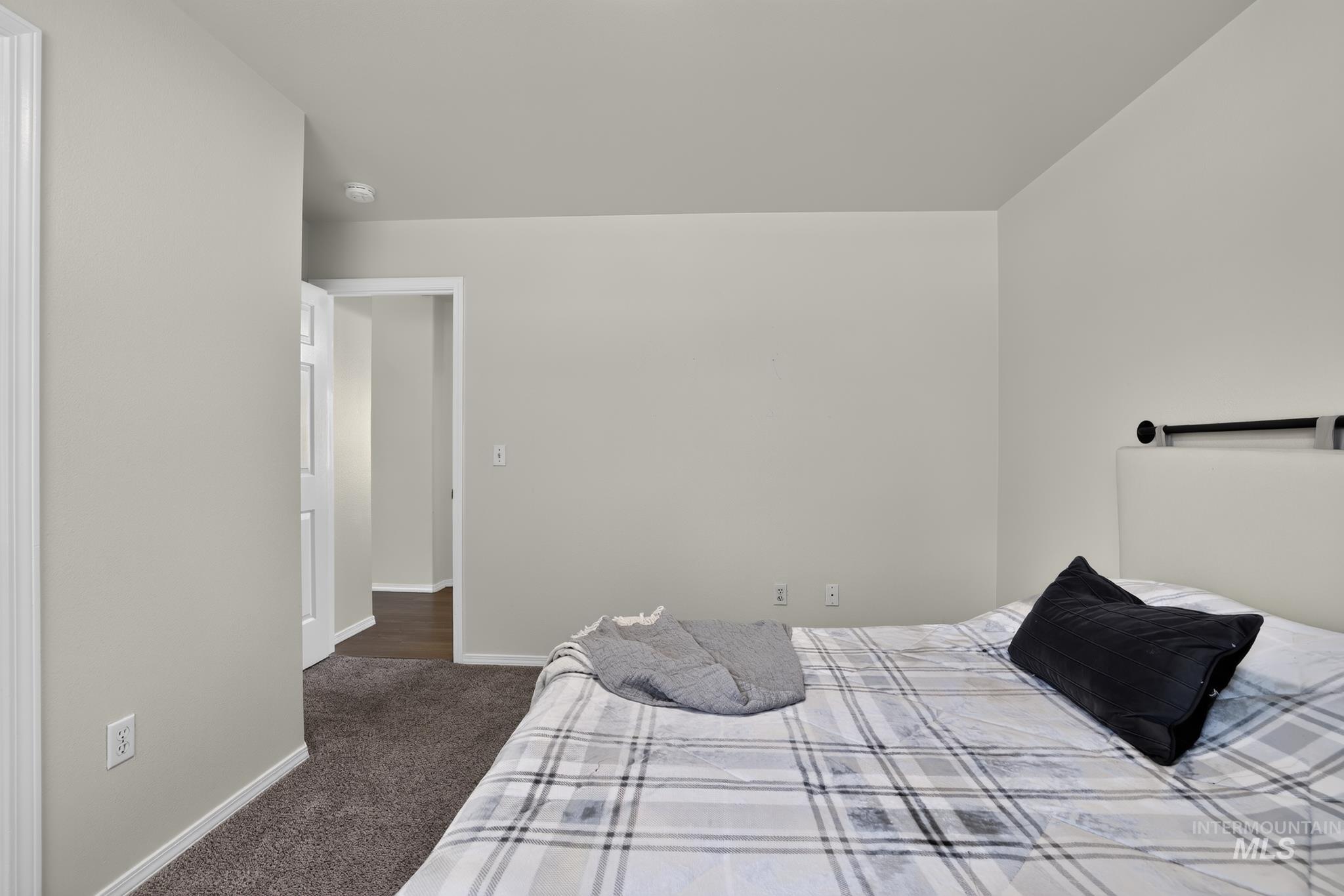 Spacious room featuring neutral wall paint, white trim, and dark carpet flooring