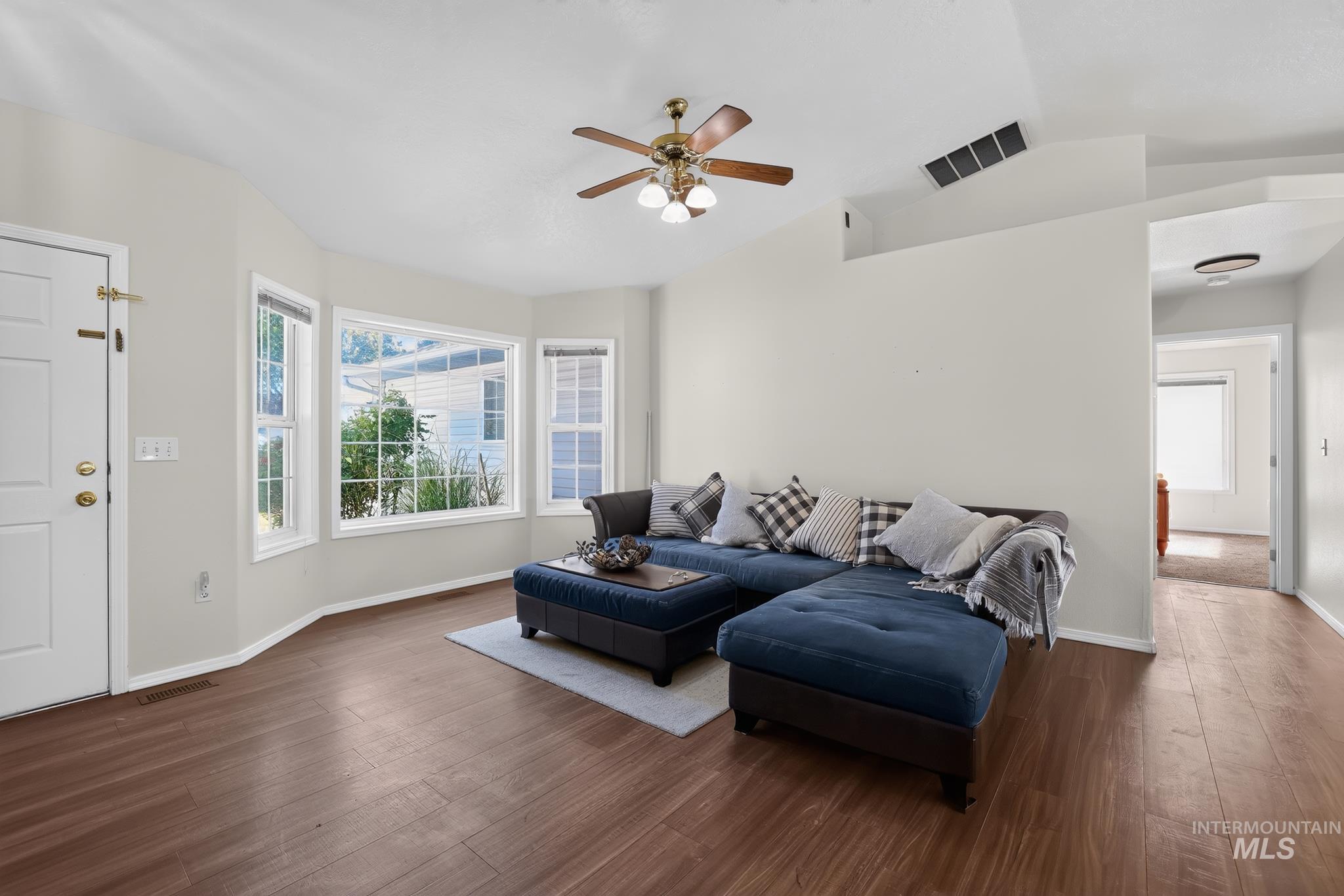 Living room with wood-finish flooring and a bay window featuring multiple panes