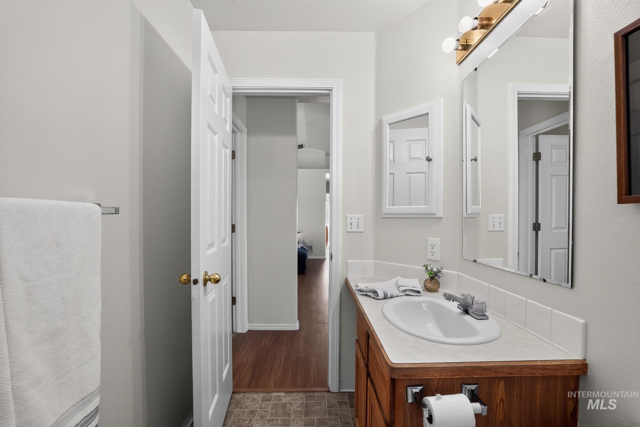 Bathroom featuring a wood-finish vanity with an integrated sink, laminate countertop, and medicine cabinet