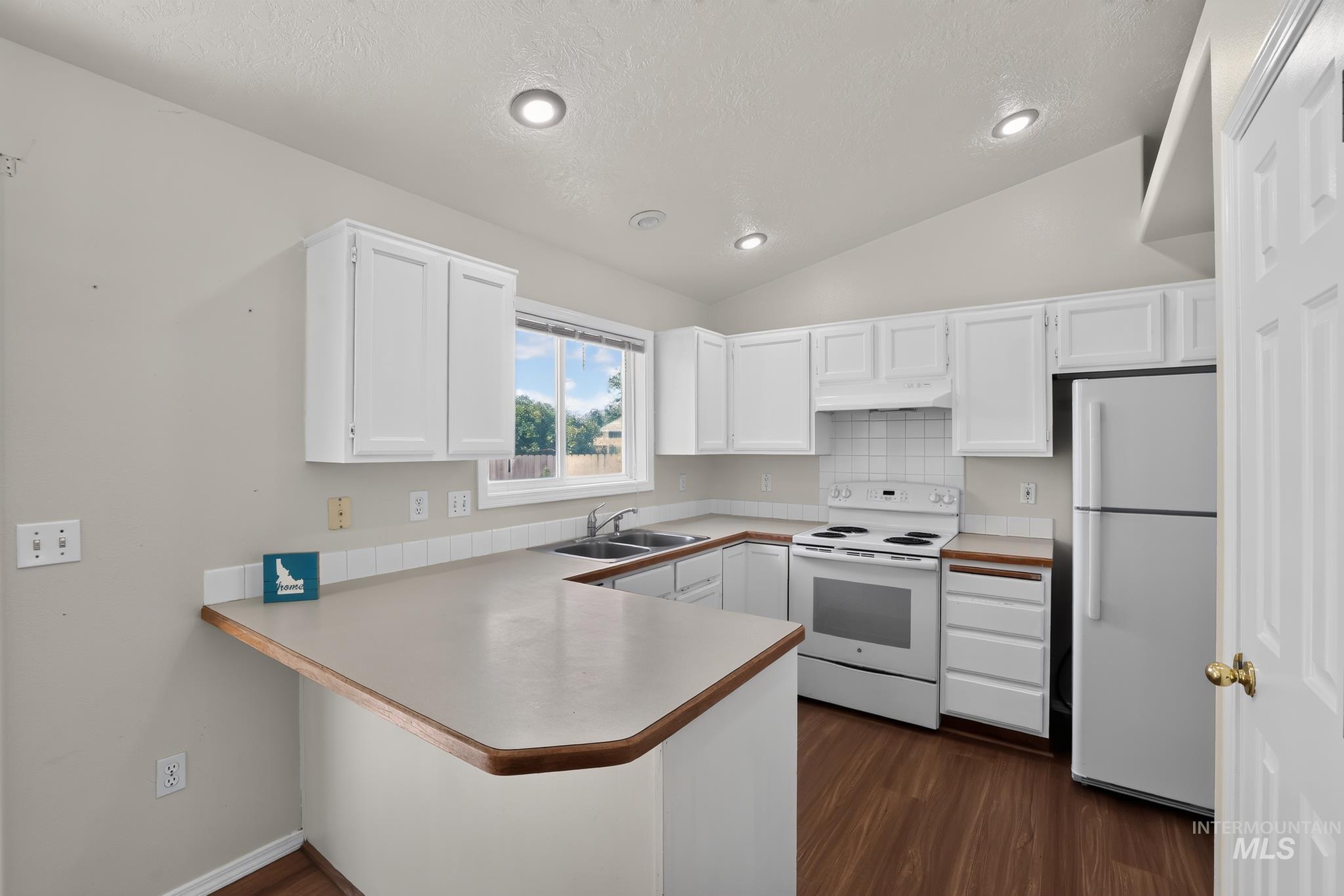 Kitchen featuring white cabinetry, wood-finish flooring, recessed lighting, a white tile backsplash, and a double basin stainless steel sink