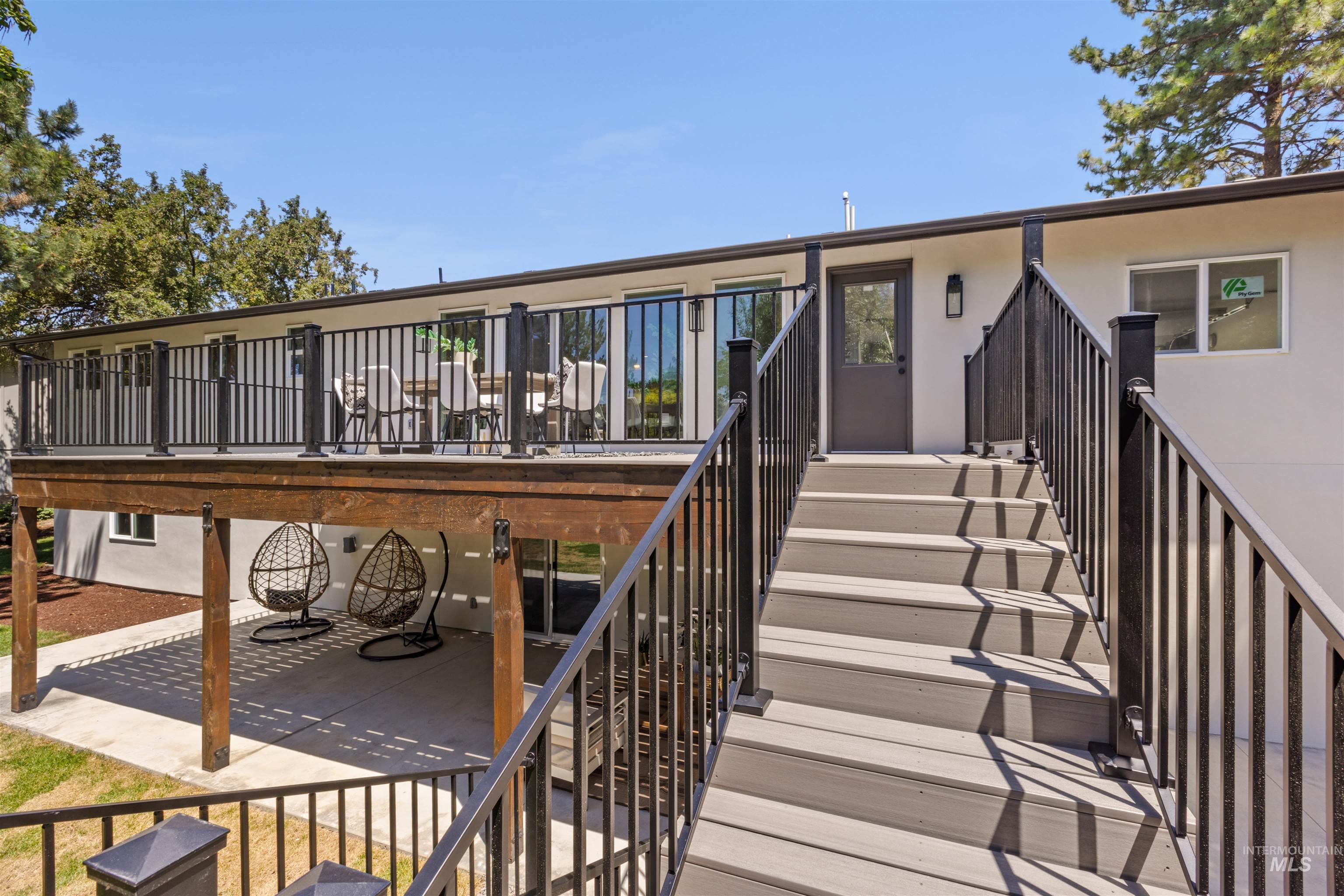 Back of house with stairs, a patio area, stucco siding, and a deck