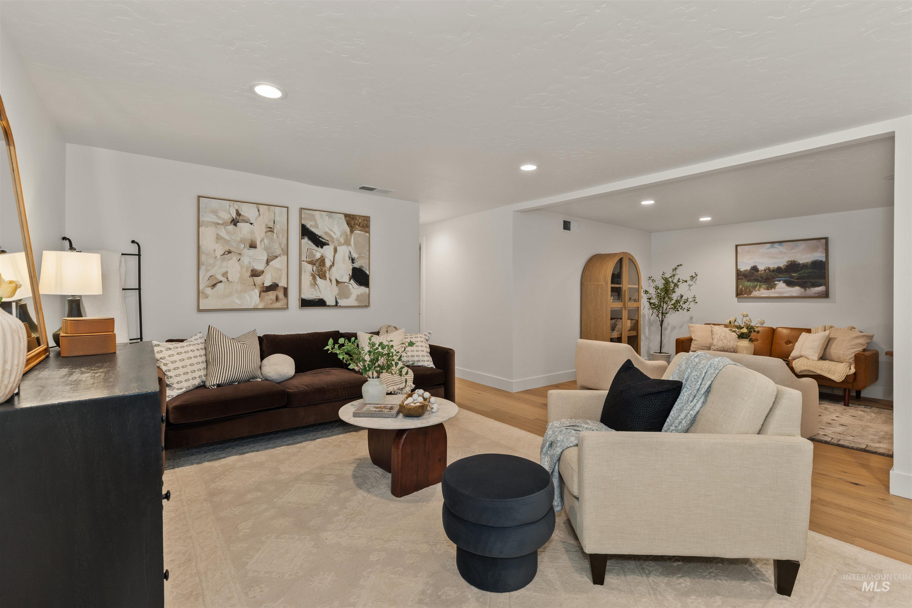 Living area featuring arched walkways, light wood finished floors, and recessed lighting