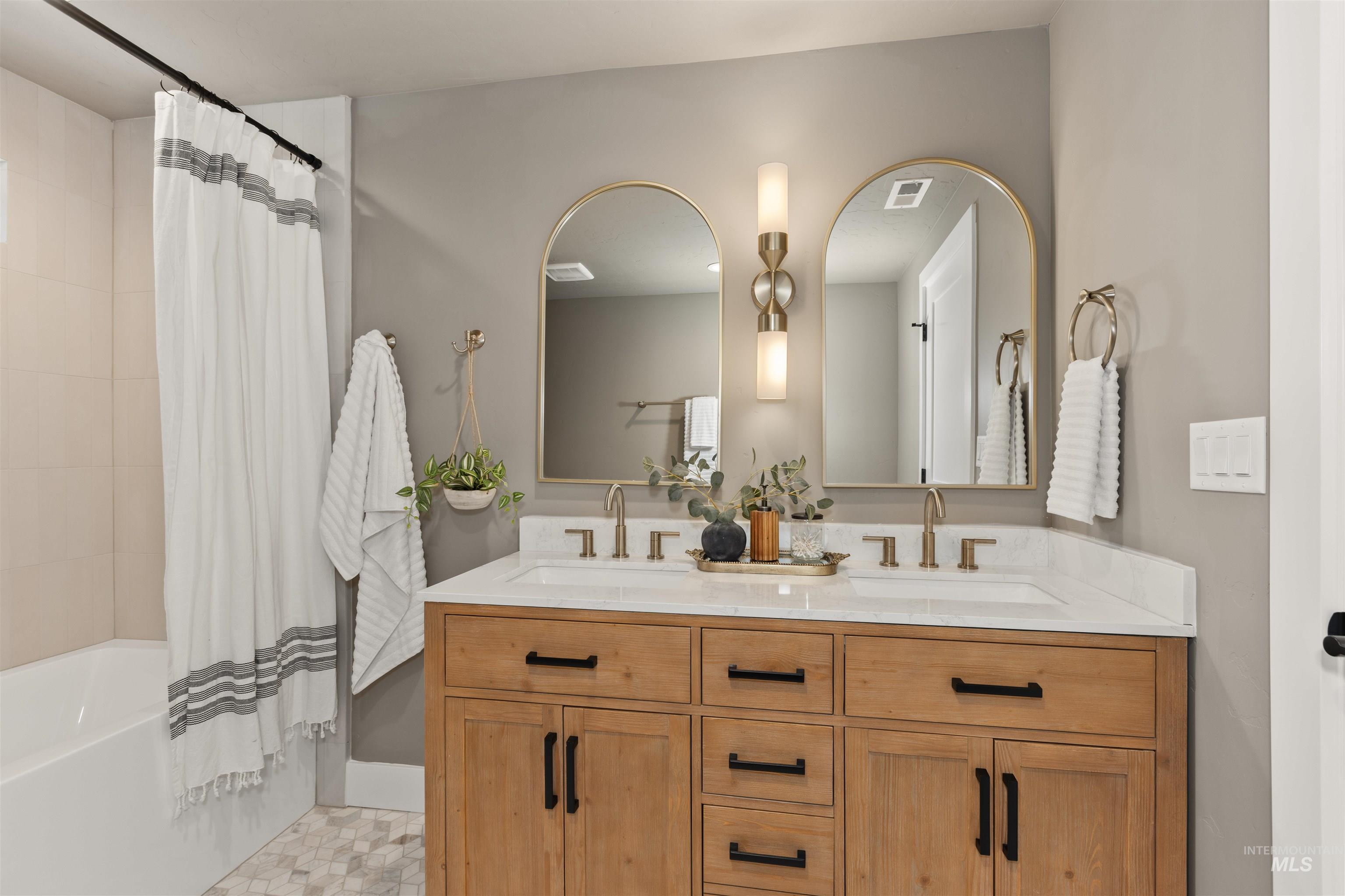 Full bath featuring shower / bath combination with curtain, double vanity, and light tile patterned floors