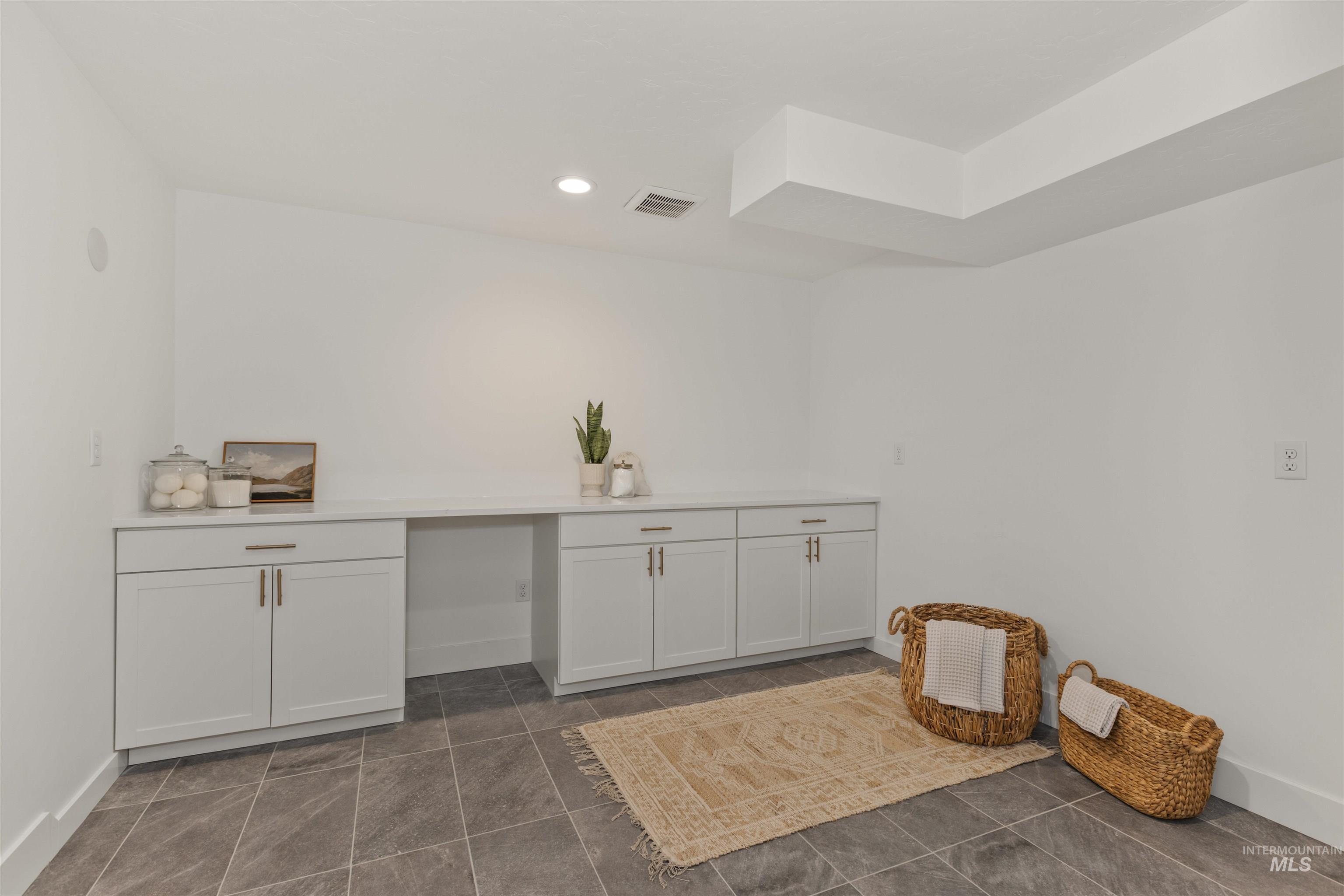 Laundry area featuring recessed lighting and dark tile patterned floors
