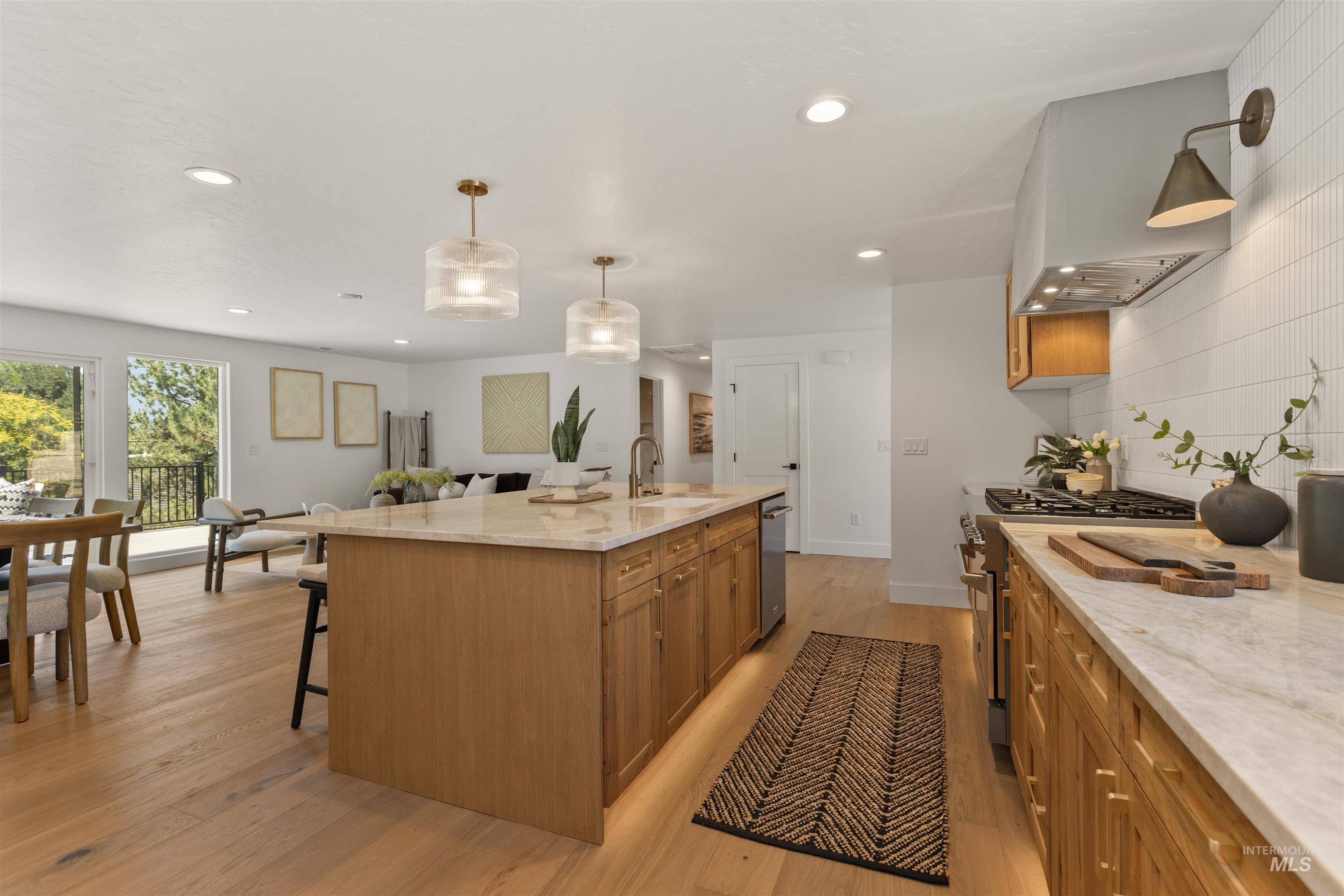 Kitchen with light stone countertops, brown cabinetry, light wood-style floors, decorative light fixtures, and recessed lighting
