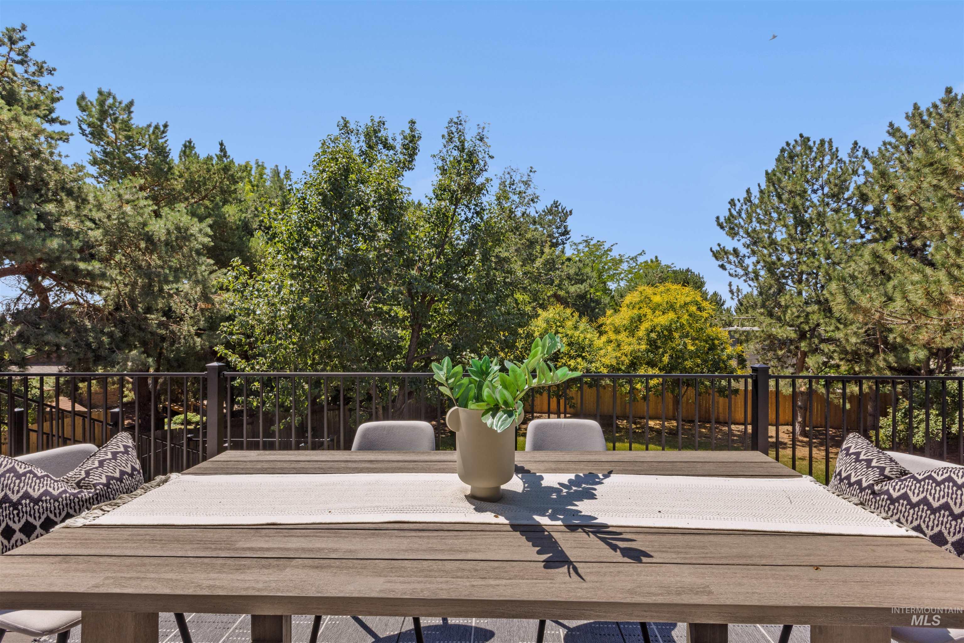 Deck with outdoor dining area and view of wooded area