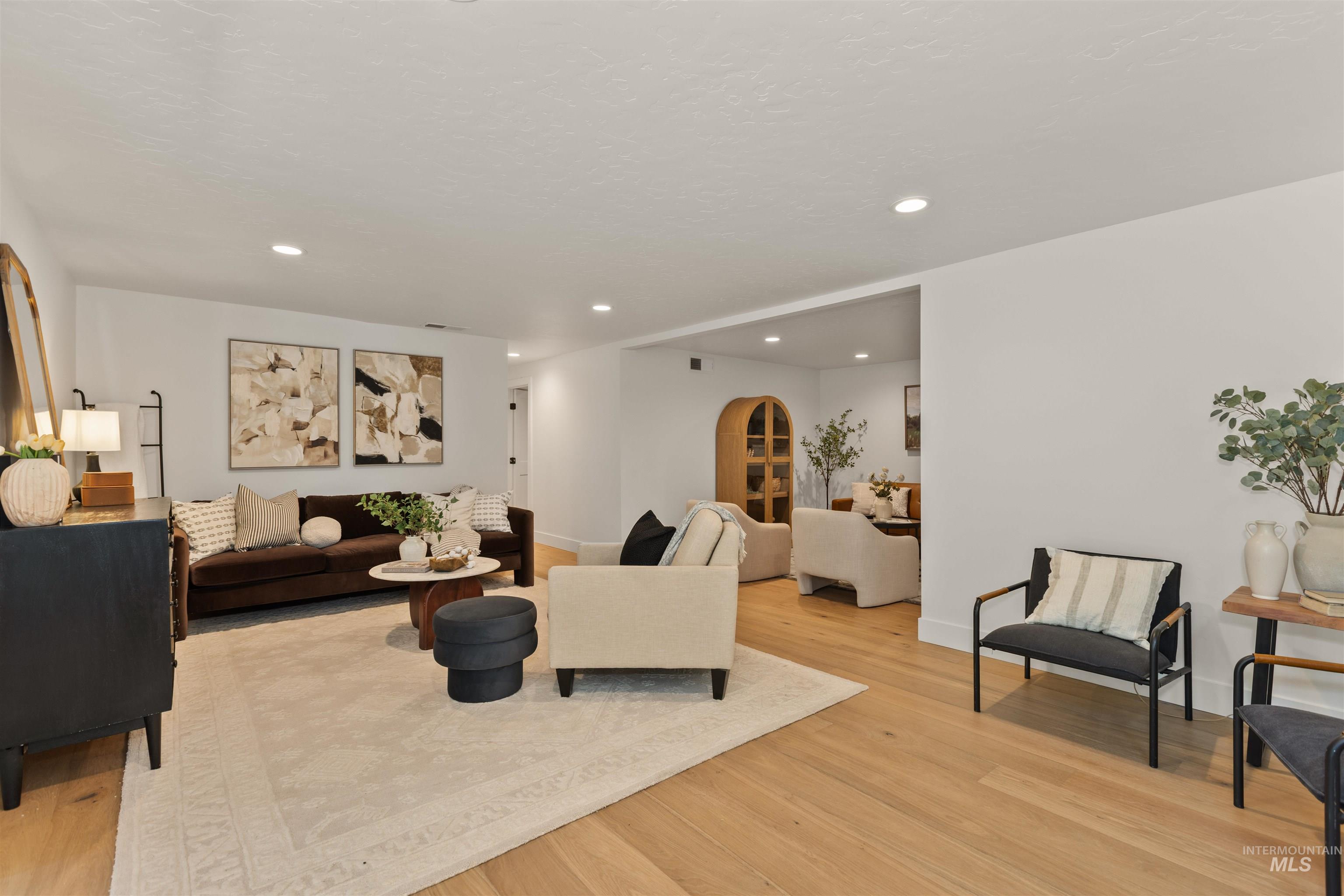 Living area featuring arched walkways, light wood-type flooring, and recessed lighting