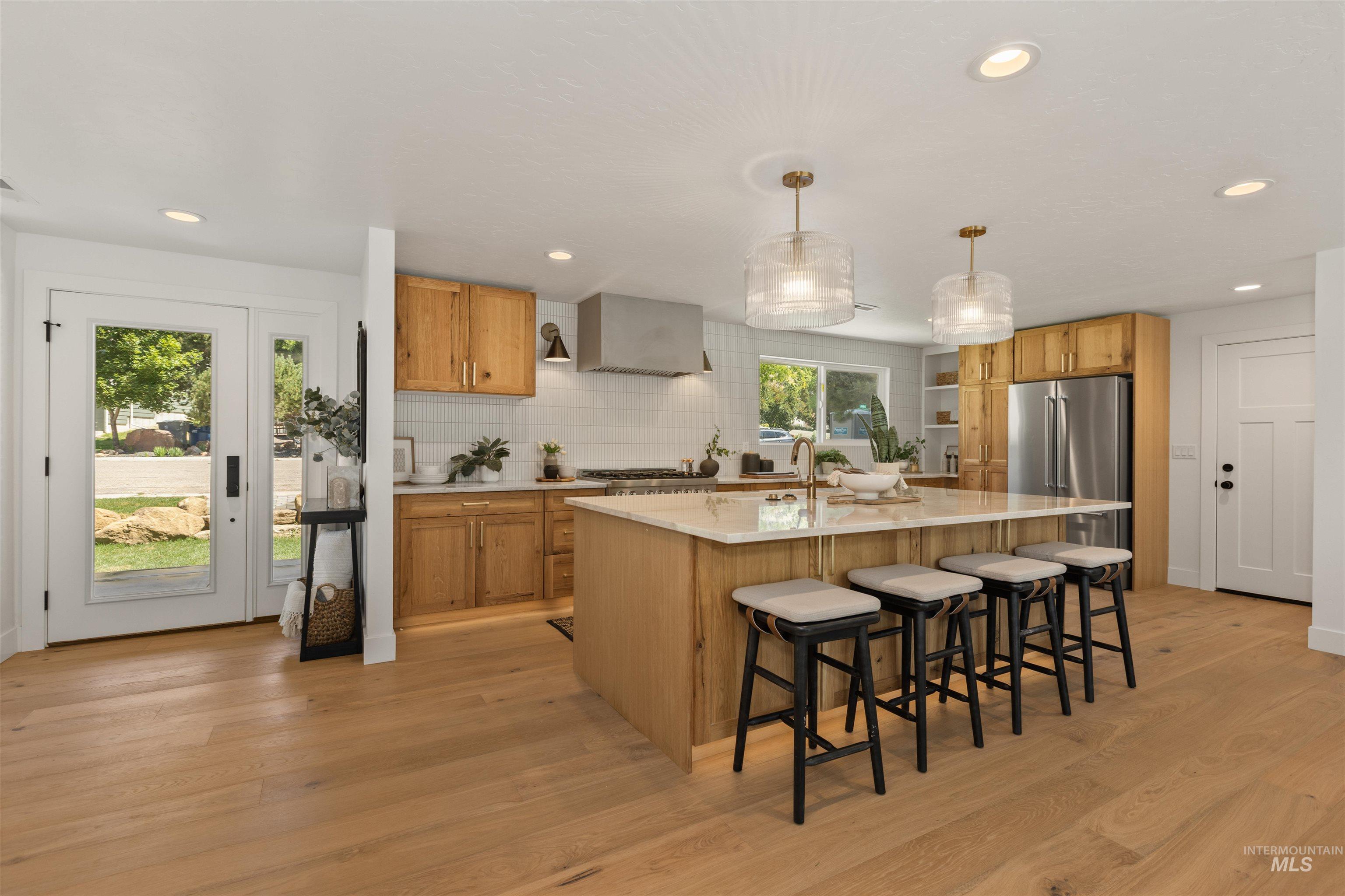 Kitchen featuring a kitchen bar, decorative light fixtures, tasteful backsplash, recessed lighting, and light wood-style floors