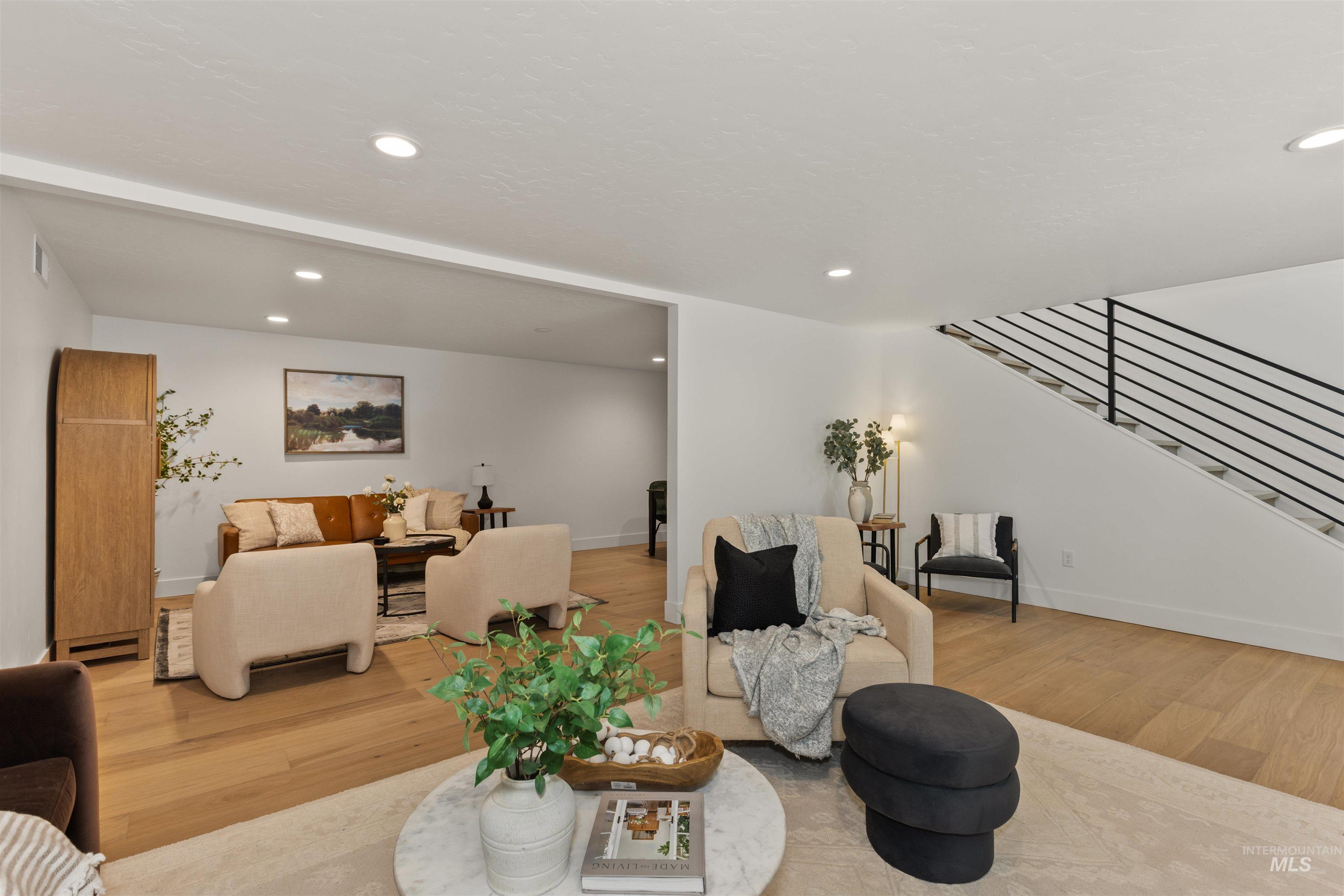 Living room with recessed lighting, stairway, wood finished floors, and a baseboard radiator