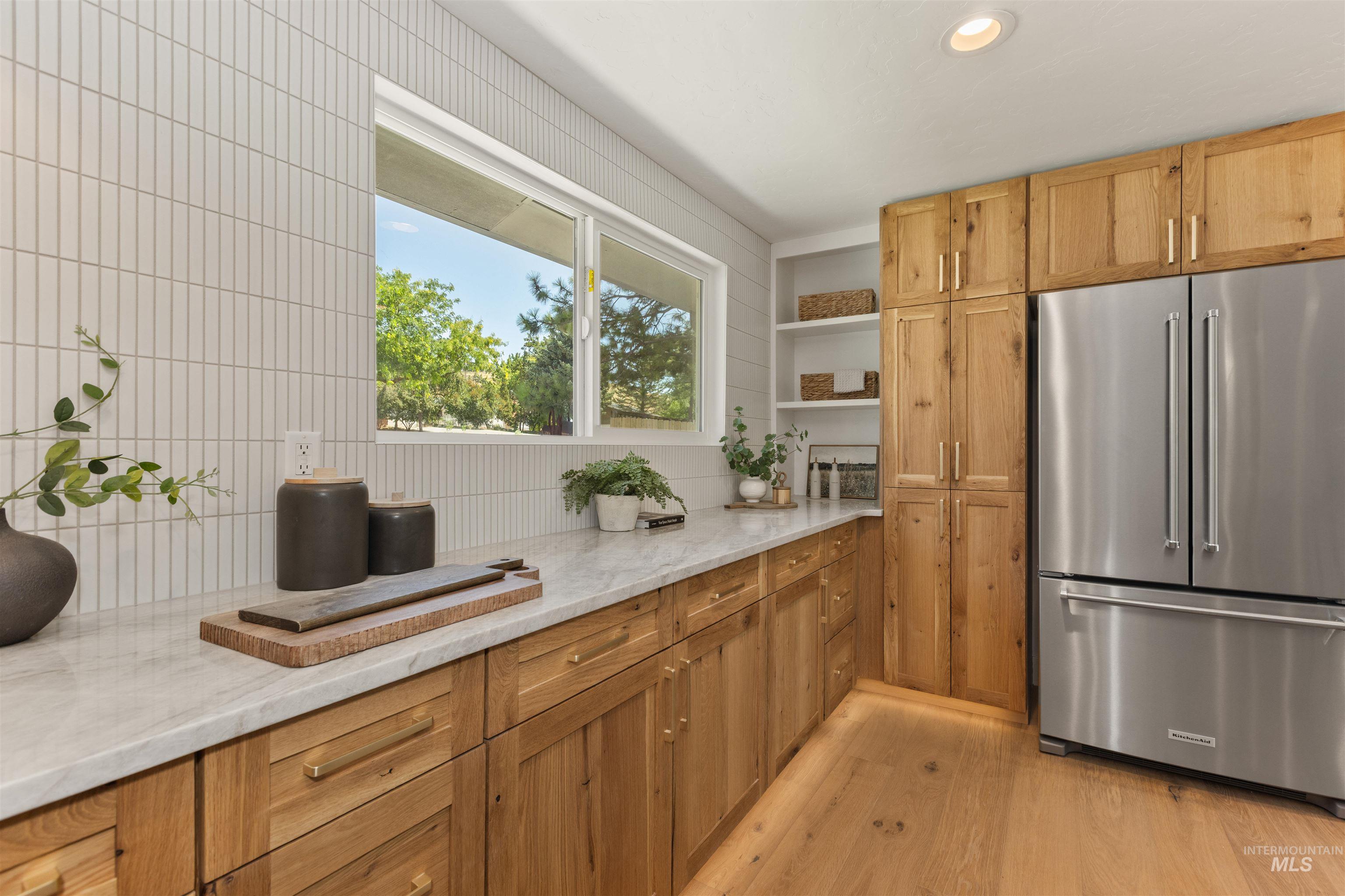 Kitchen featuring stainless steel refrigerator, light stone counters, open shelves, light wood finished floors, and recessed lighting