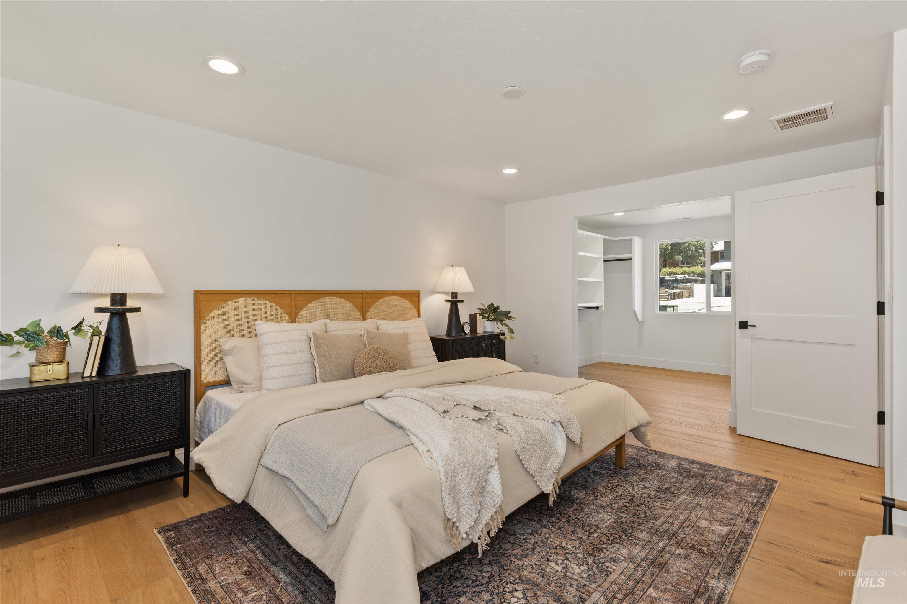 Bedroom featuring a walk in closet, light wood-type flooring, and recessed lighting