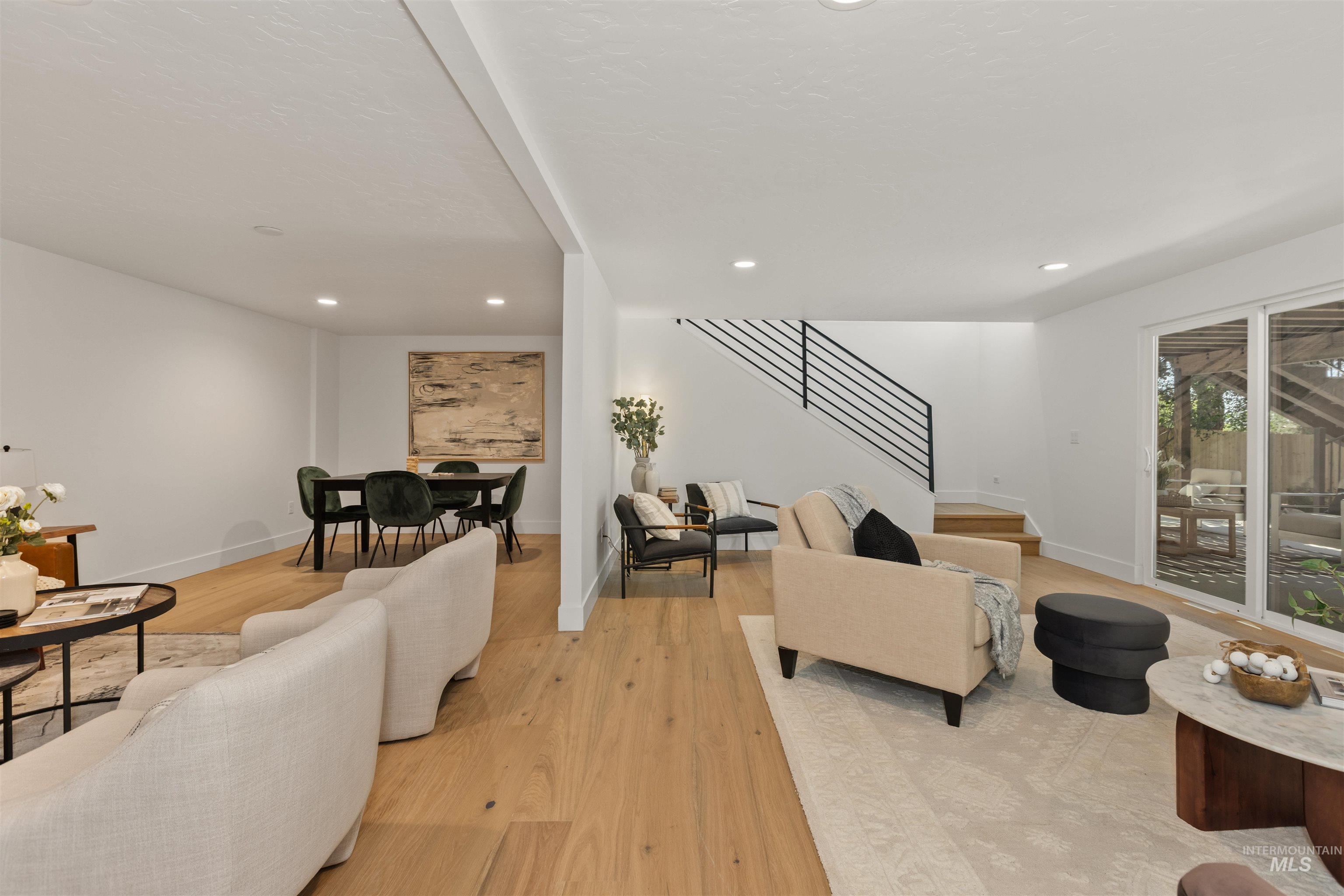 Living room with light wood finished floors, recessed lighting, and stairs