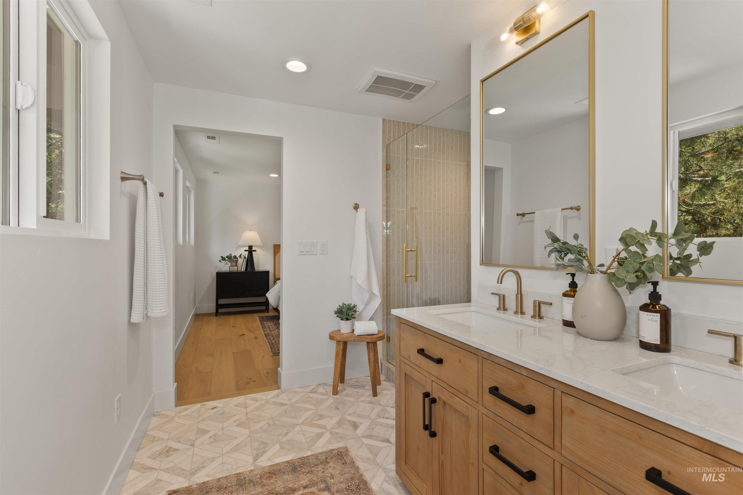 Bathroom featuring healthy amount of natural light, a shower stall, double vanity, connected bathroom, and recessed lighting