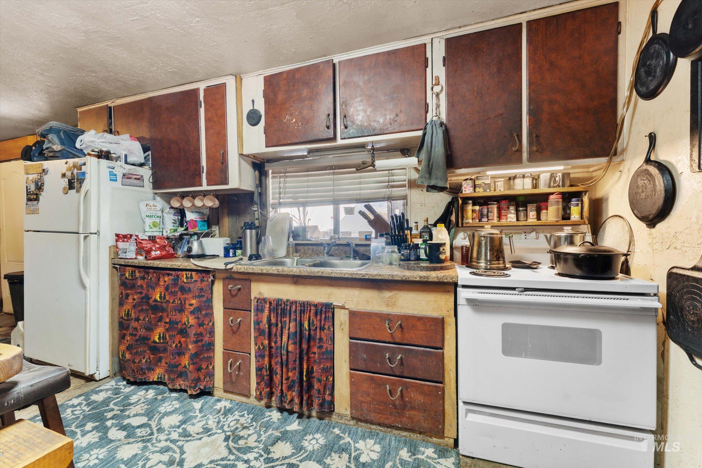 Kitchen with white appliances, light countertops, and a textured ceiling