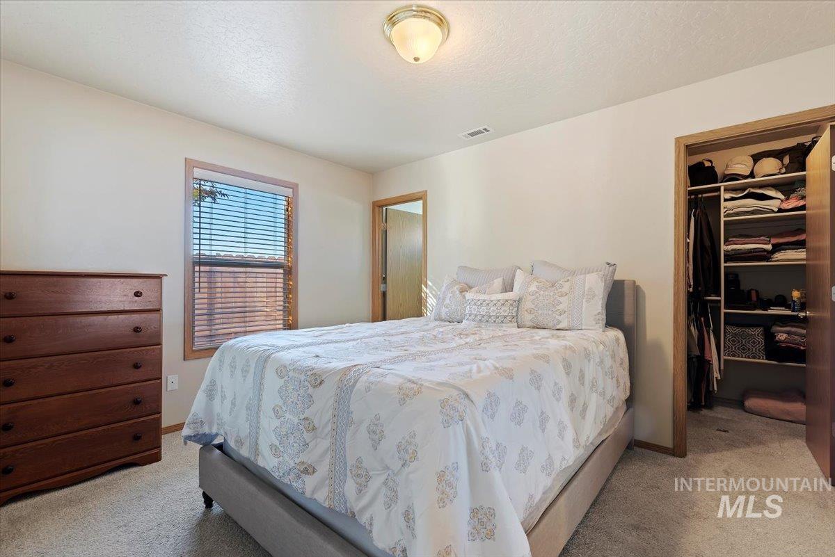 Bedroom featuring a spacious closet, light colored carpet, and a textured ceiling