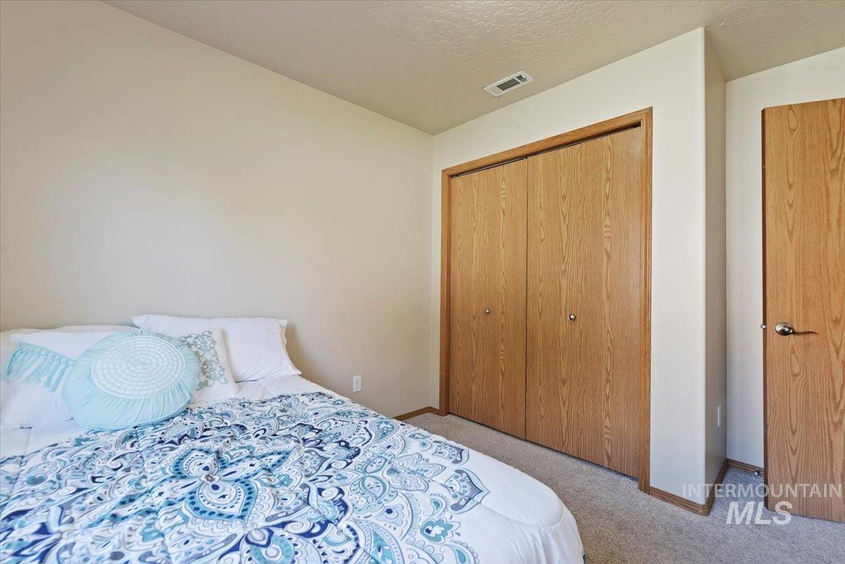 Bedroom with carpet floors, a closet, and a textured ceiling