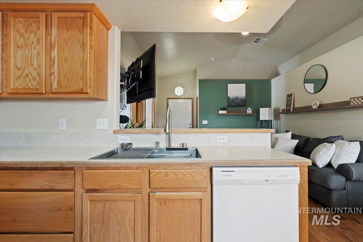 Kitchen with light countertops, dishwasher, open floor plan, a peninsula, and light brown cabinets