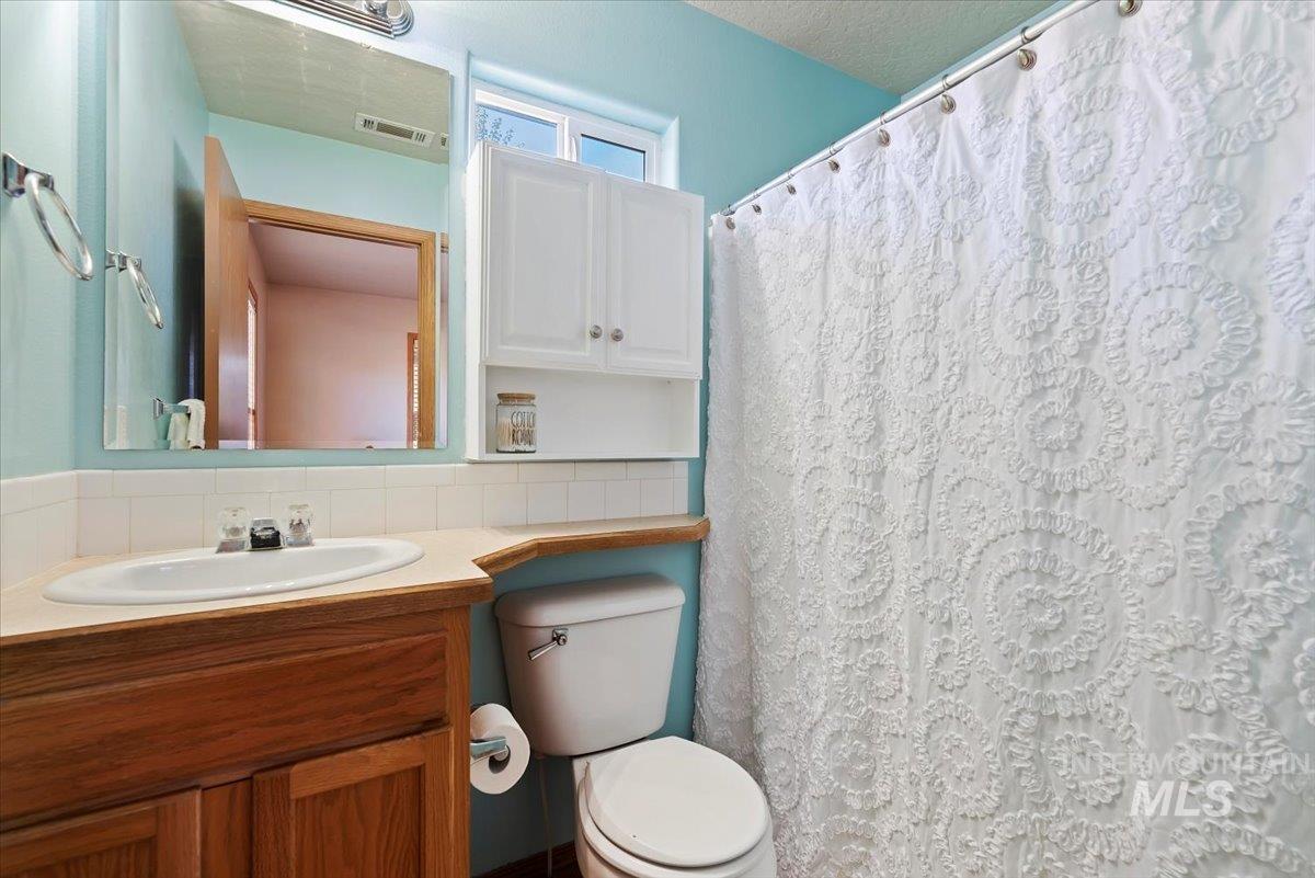 Full bath featuring curtained shower, vanity, backsplash, and a textured ceiling