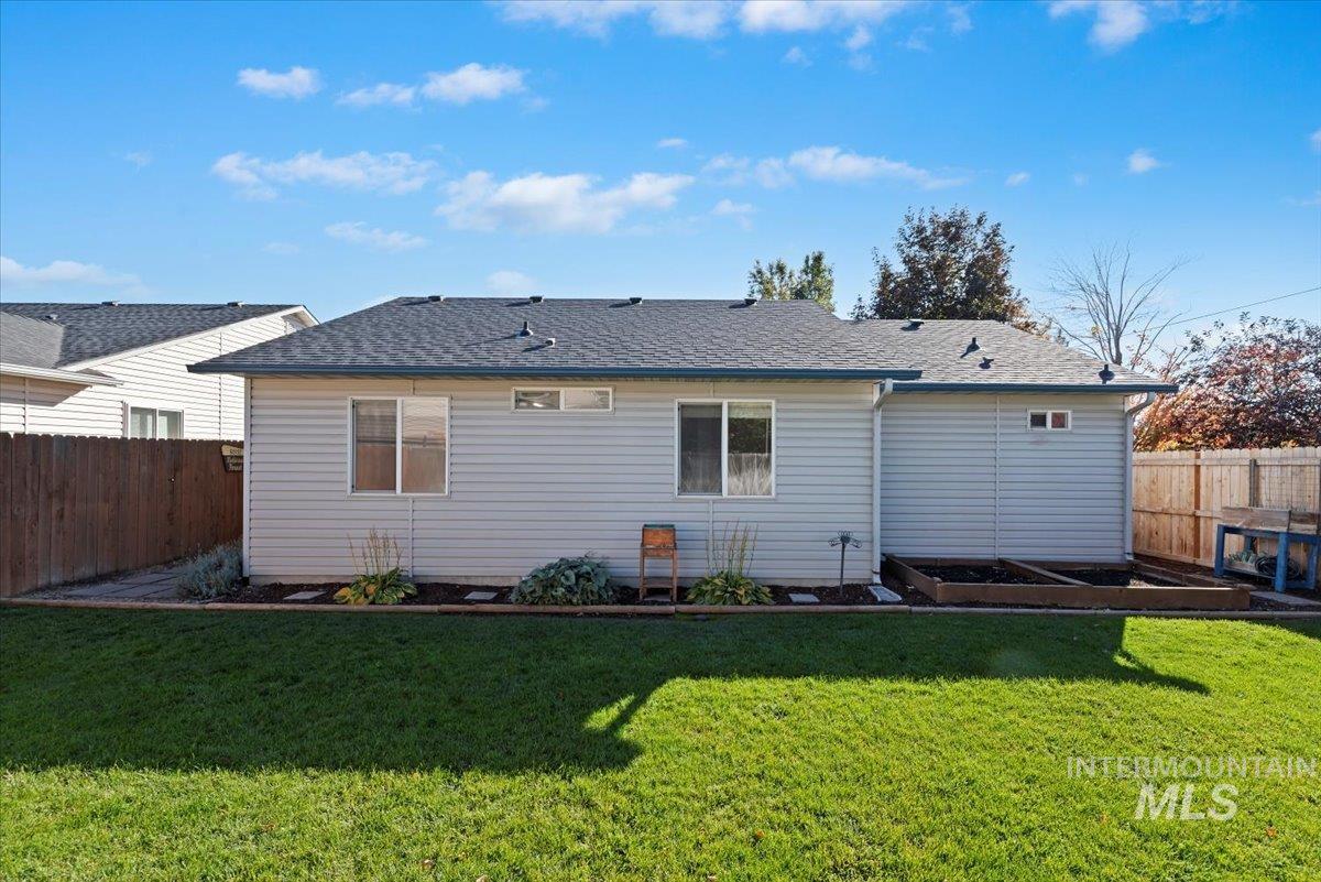 Rear view of property featuring a fenced backyard, a vegetable garden, and a shingled roof