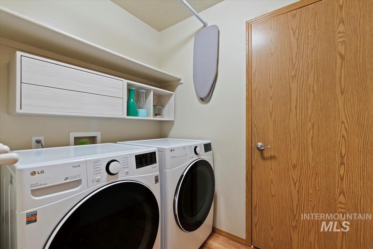 Laundry area with washer and dryer and light wood-type flooring