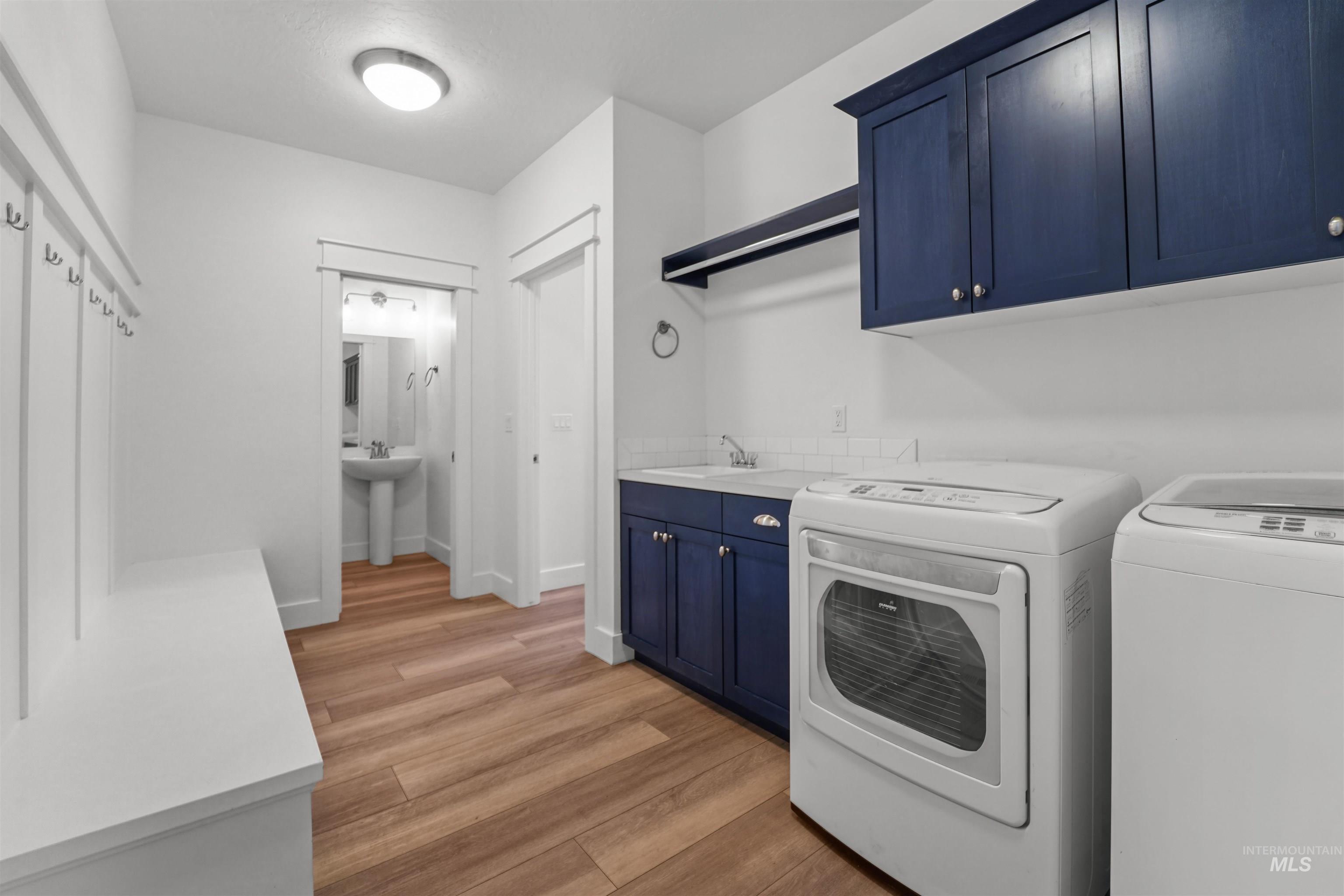 Laundry area with cabinet space, washer and clothes dryer, and light wood-style floors