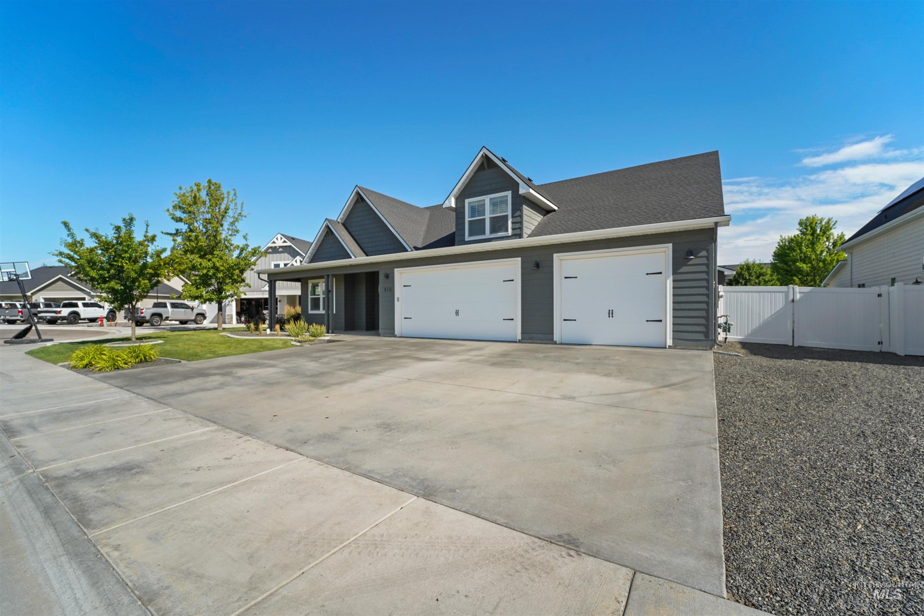 View of front of property featuring concrete driveway, a gate, an attached garage, and a shingled roof