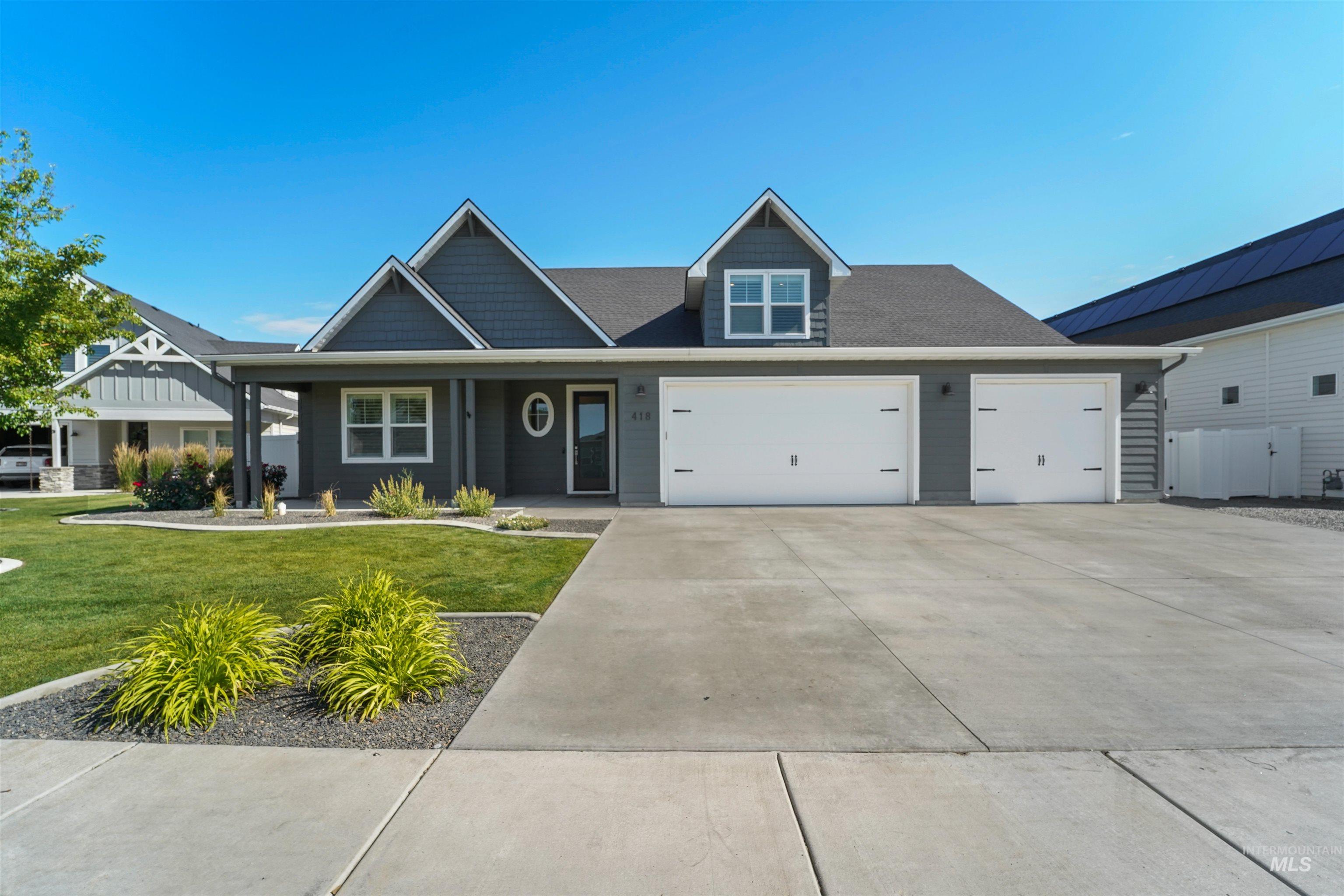 View of front of house with an attached garage, a front yard, concrete driveway, and covered porch