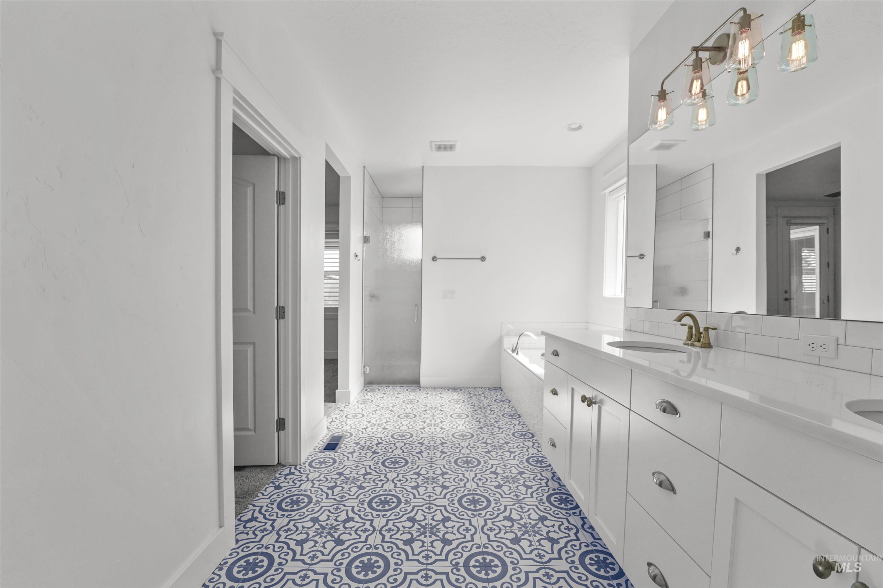 Full bathroom featuring a tub to relax in, double vanity, and a shower
