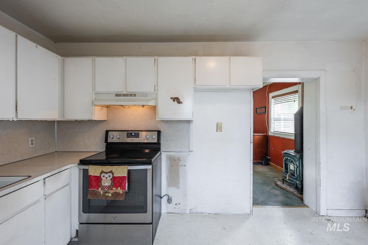 Kitchen featuring white cabinetry, a stainless steel range, and a built-in range hood