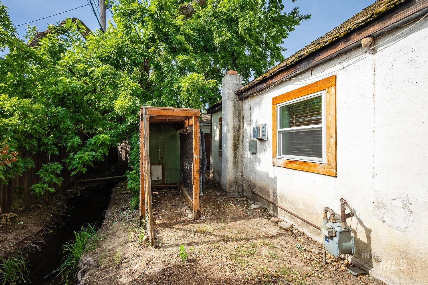 Exterior side of the property featuring a white stucco finish and a single-pane window with wood-frame trim