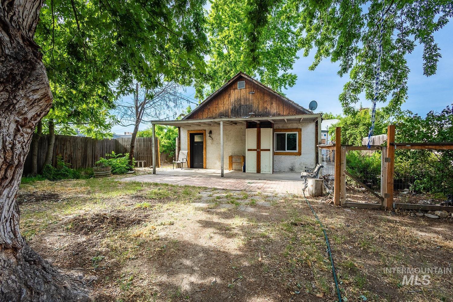 Rear exterior featuring a covered patio, wood-paneled gable, and a private fenced yard with mature trees
