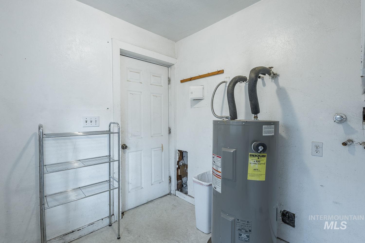 Utility area featuring a water heater, white paneled door, and exposed conduit