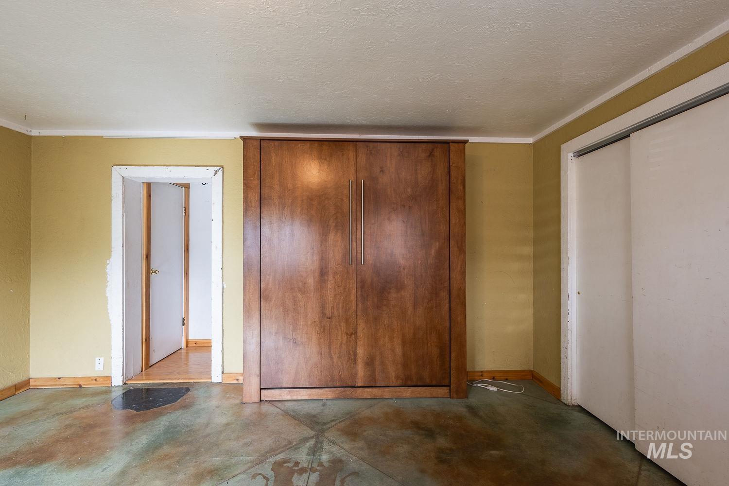 Built-in wood-finish cabinetry featuring vertical hardware, complemented by a distressed concrete floor