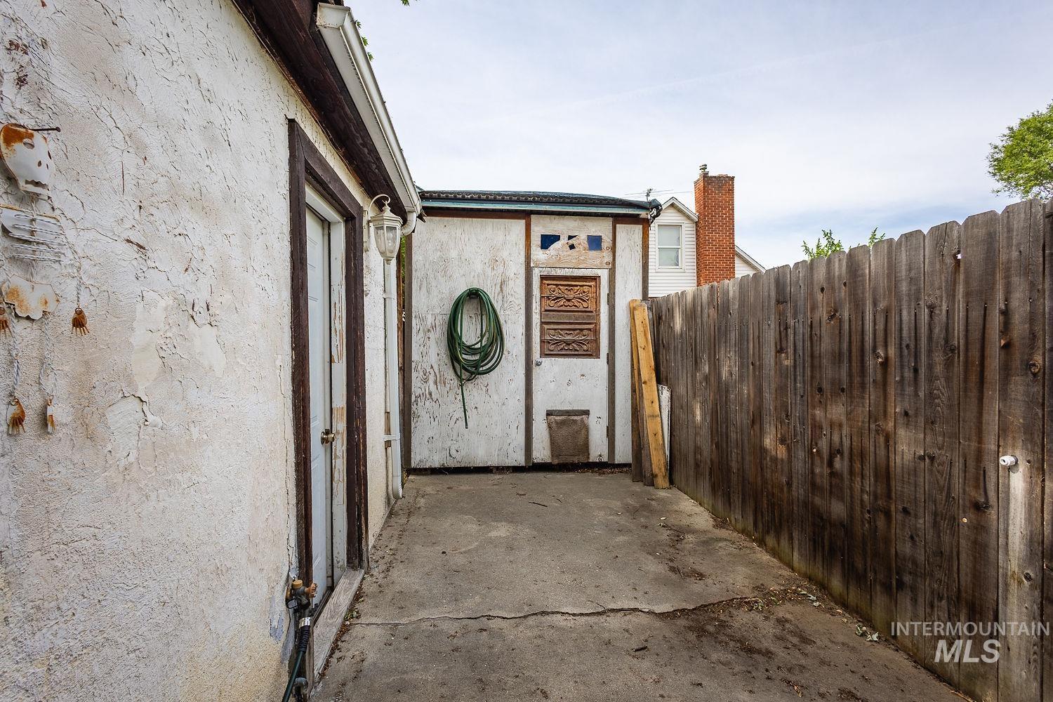 Outdoor paved walkway featuring a privacy fence and exterior stucco walls