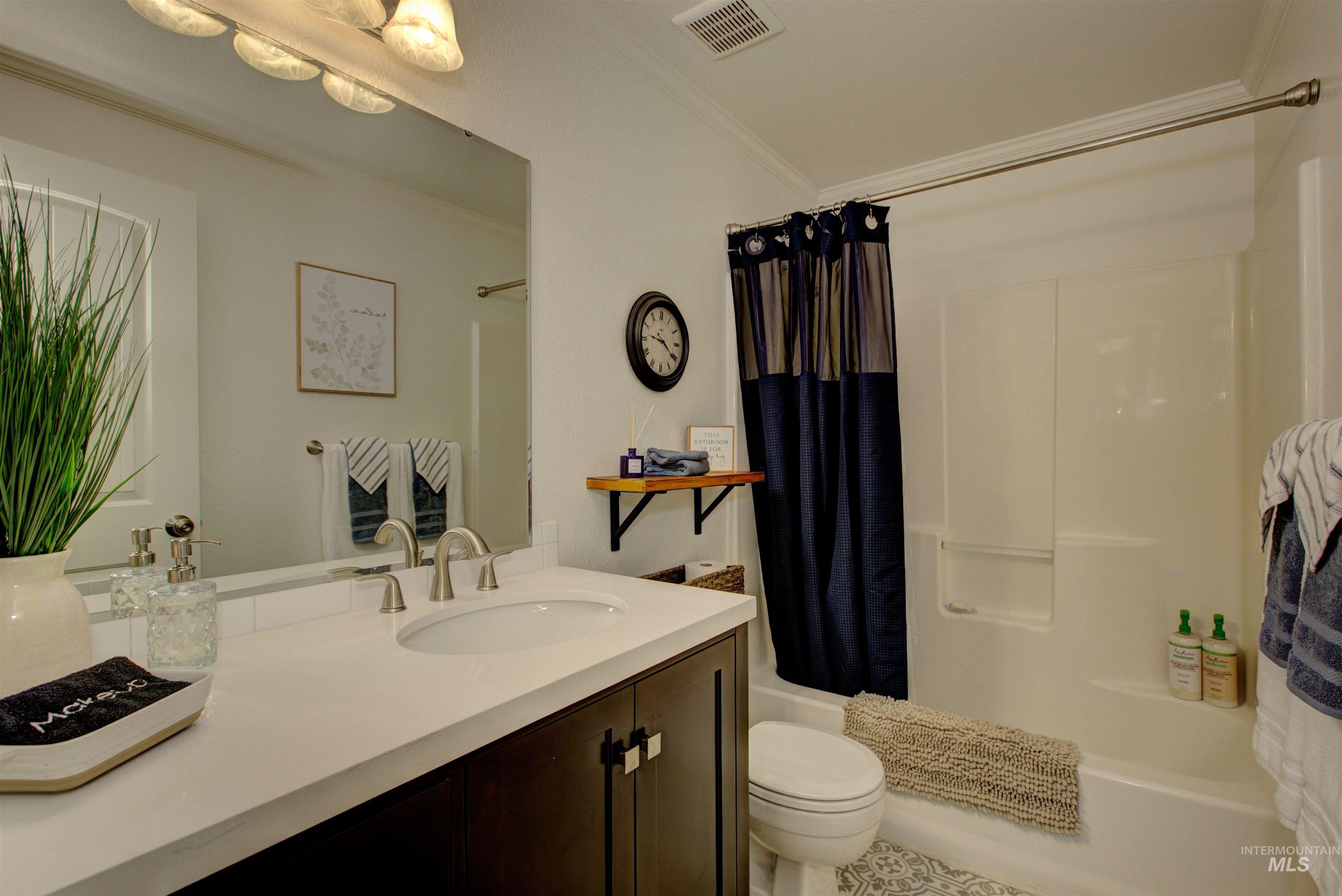 Full bathroom with vanity, shower / tub combo with curtain, and crown molding