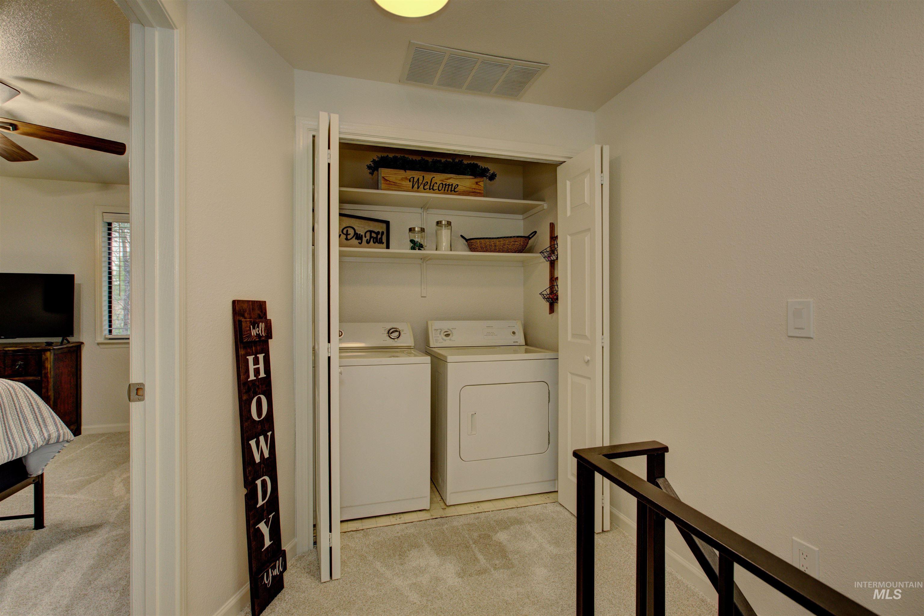 Washroom with washer and clothes dryer, light colored carpet, and a ceiling fan