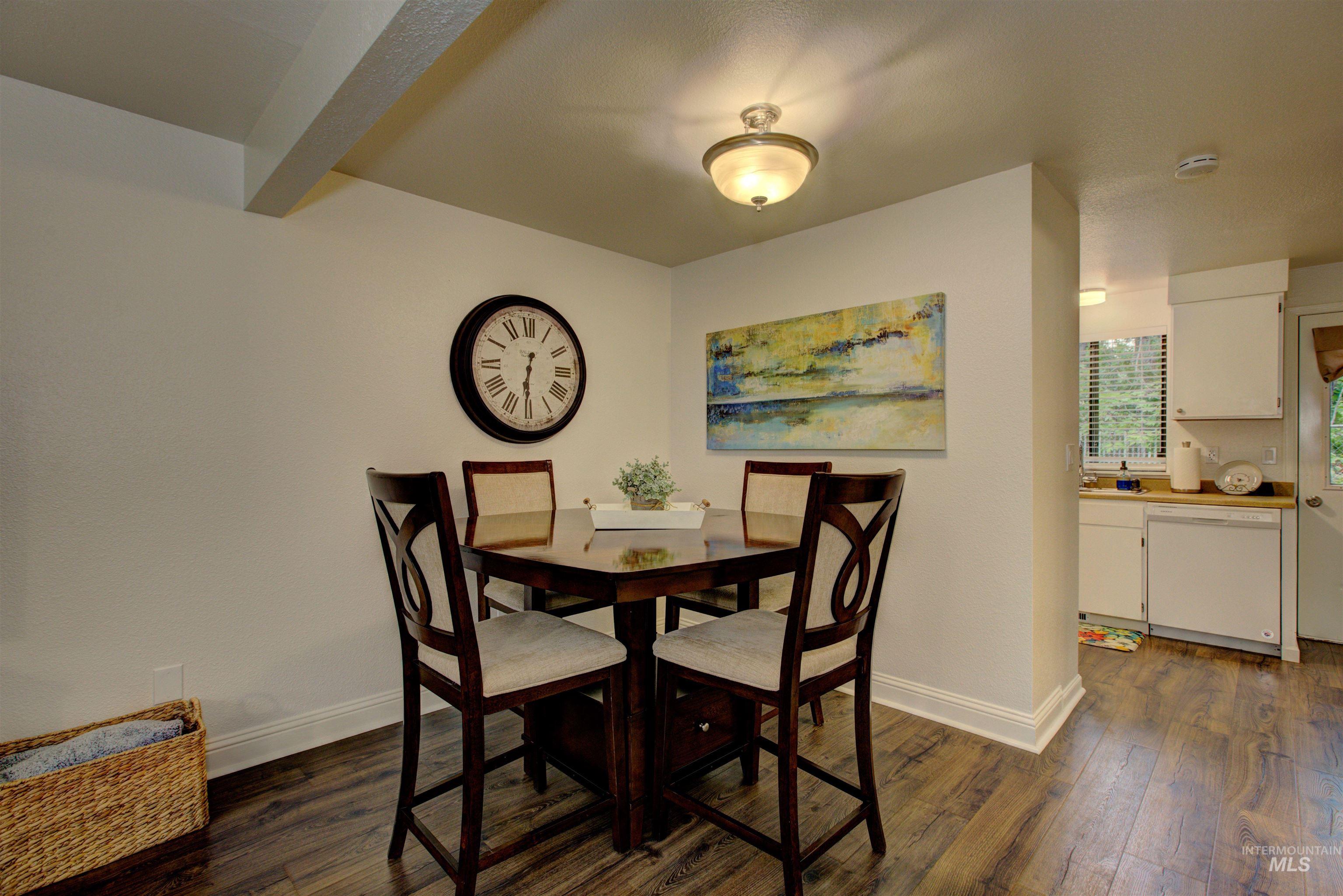 Dining area featuring dark wood-style flooring and beamed ceiling