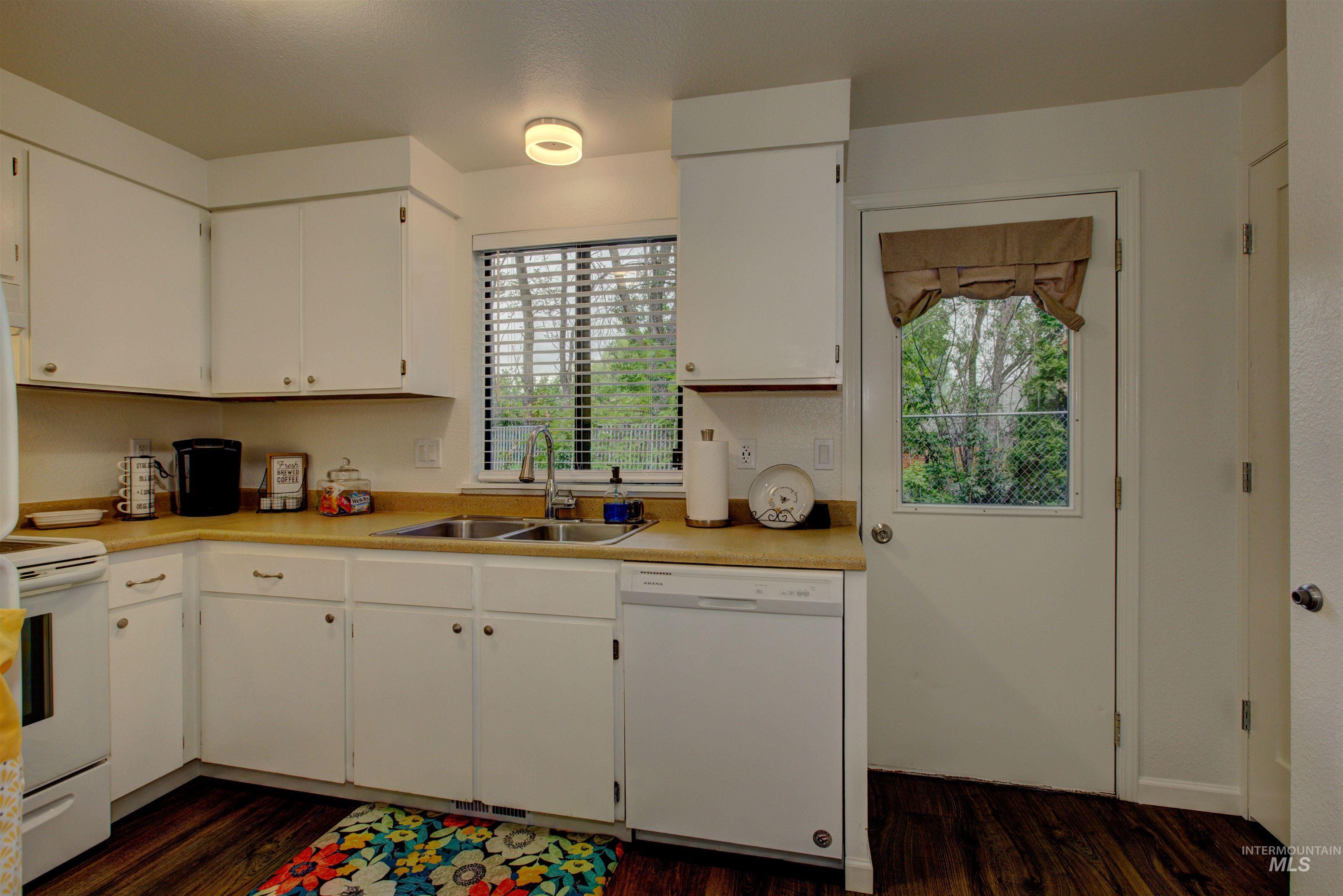 Kitchen with white appliances, dark wood-style flooring, and white cabinets