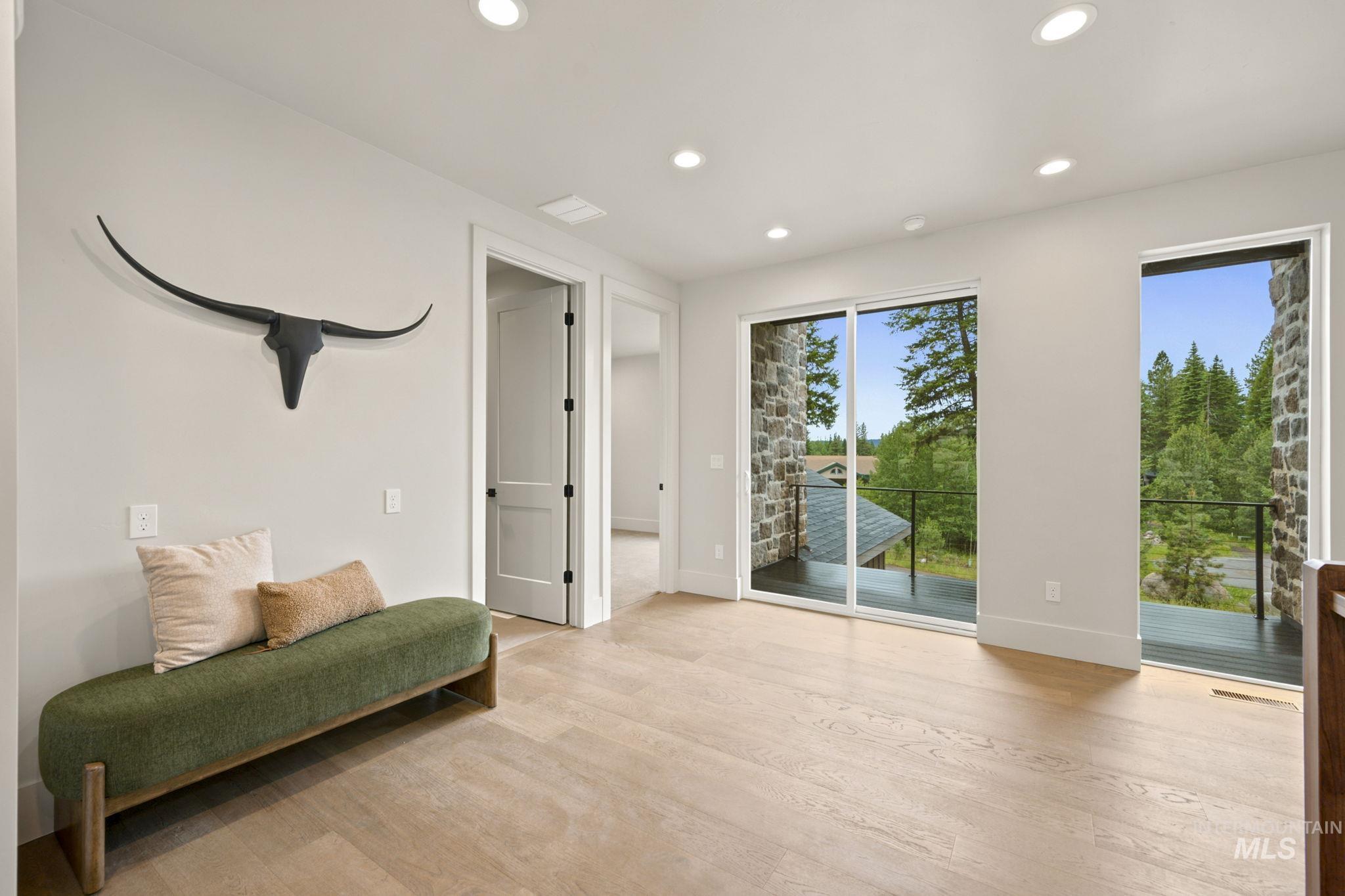 Bright interior space featuring light wood-finish flooring, recessed lighting, and a sliding glass door leading to an outdoor balcony - Top of Stairs - Second Floor