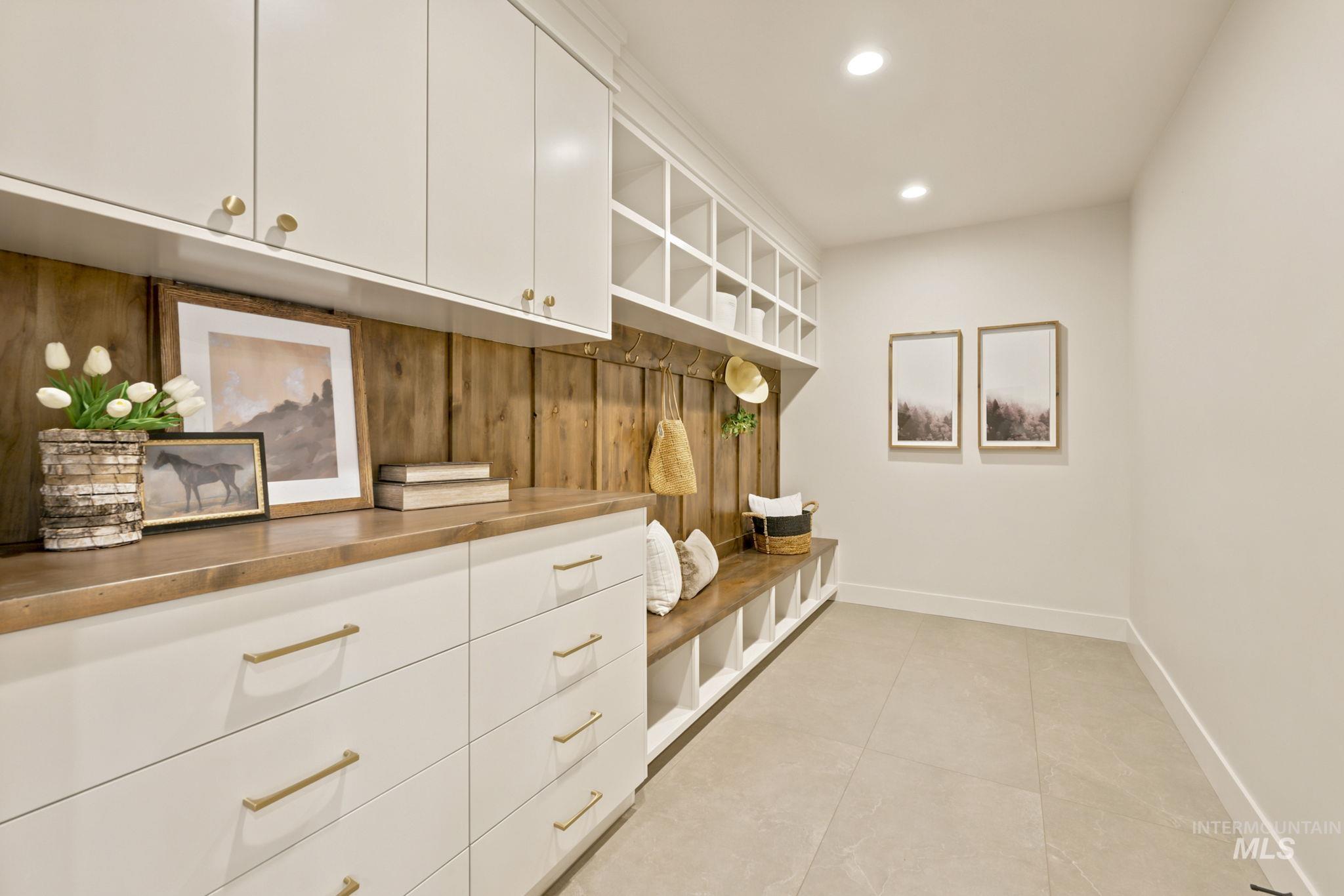 Custom mudroom featuring a built-in bench, upper cubbies, and a wood-paneled wall with hooks - Off of Garage Main floor Front Door